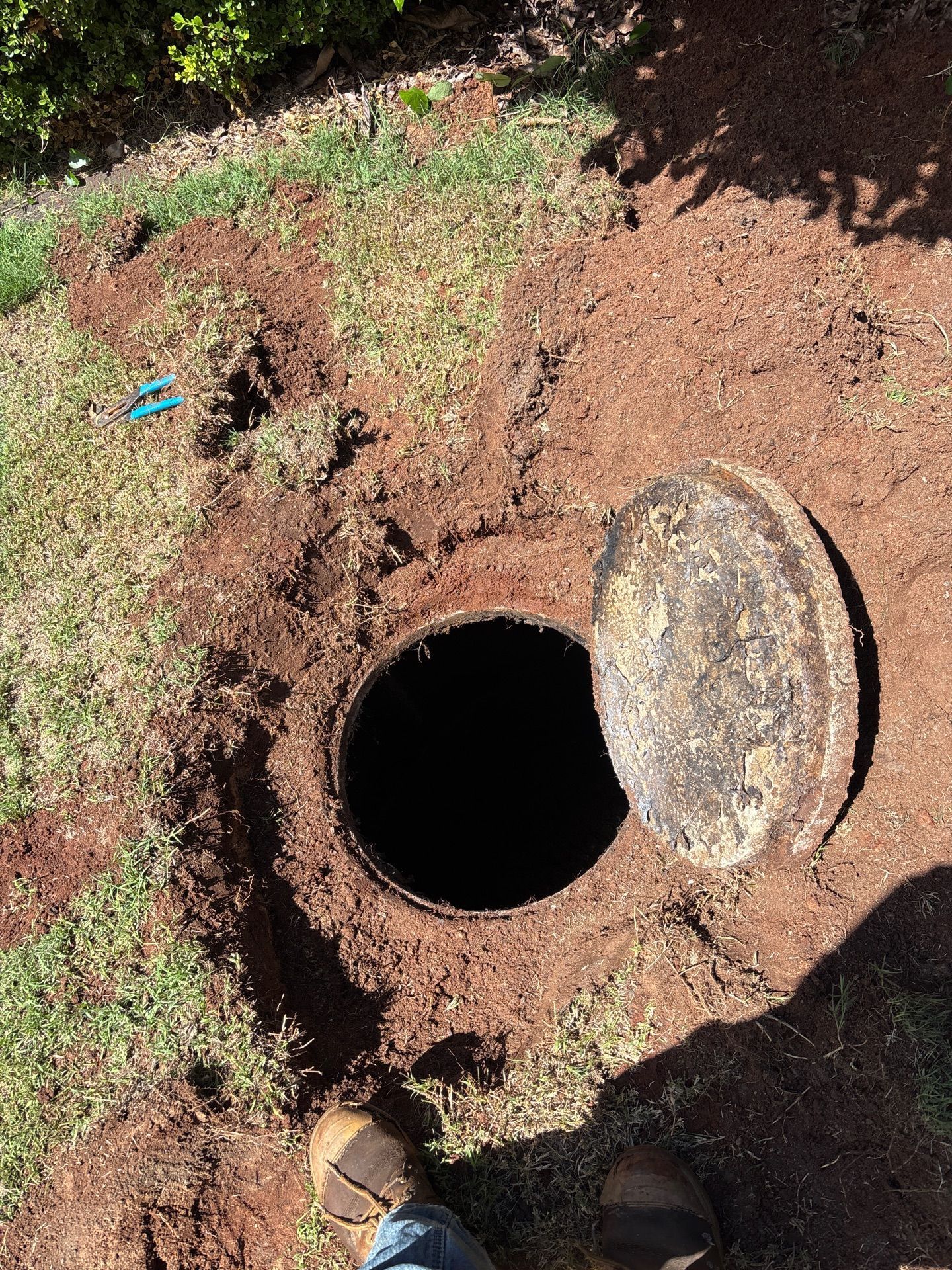 Open Manhole in Red Dirt With the Cover Propped Beside It — Shreks Septic Services in Southbrook, QLD