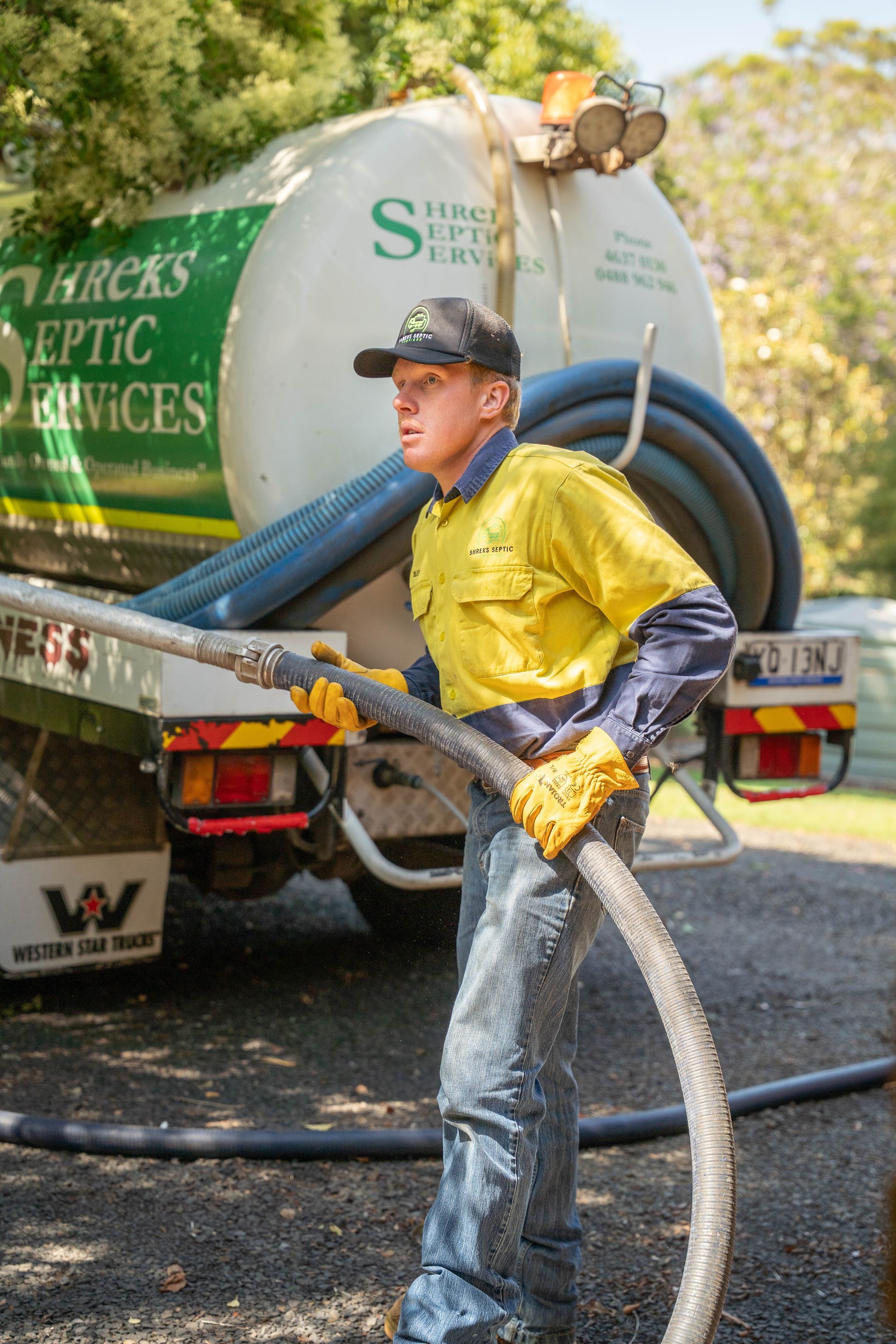 Worker in Yellow Shirt Handling a Hose — Shreks Septic Services in Cambooya, QLD