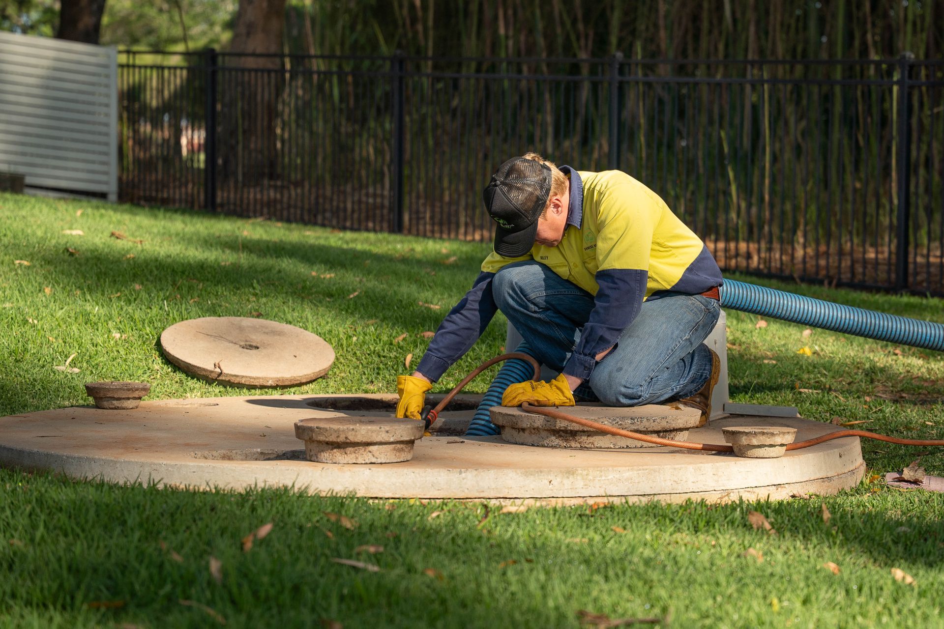Worker in Yellow Jacket Kneeling Over — Shreks Septic Services in Helidon, QLD