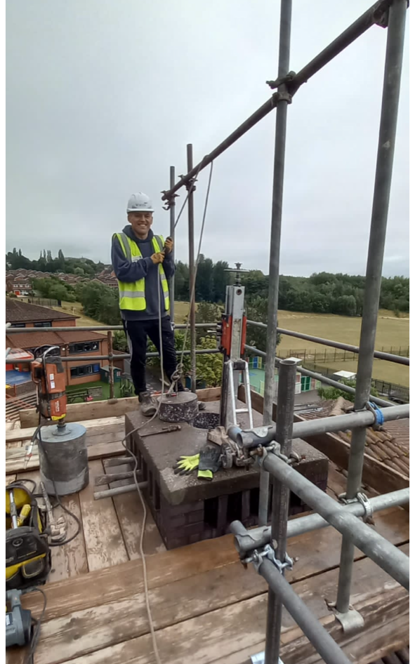 A man is standing on top of a scaffolding on a roof.