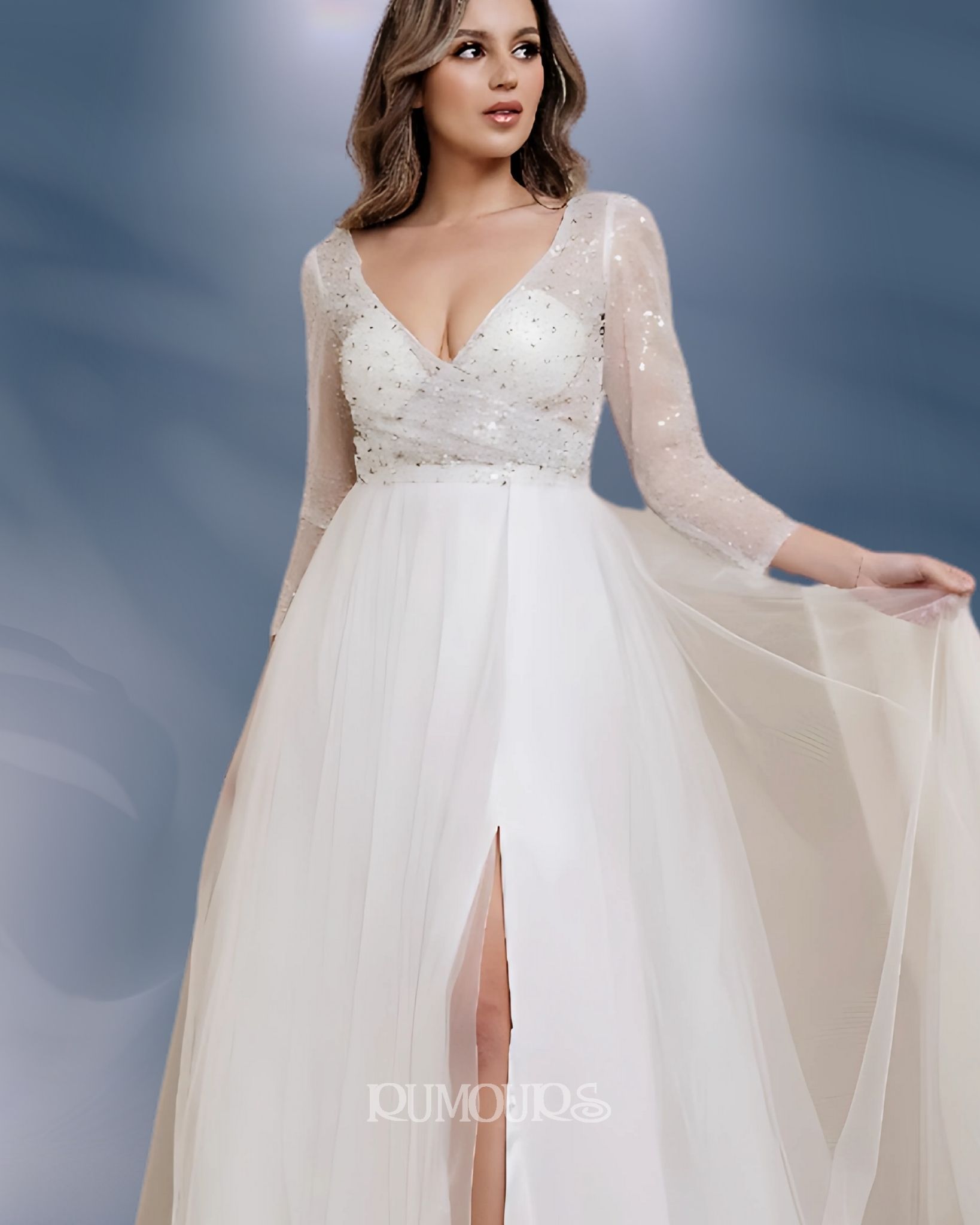 Woman in a white wedding dress with long sleeves and a high slit, posing in front of a blue background.