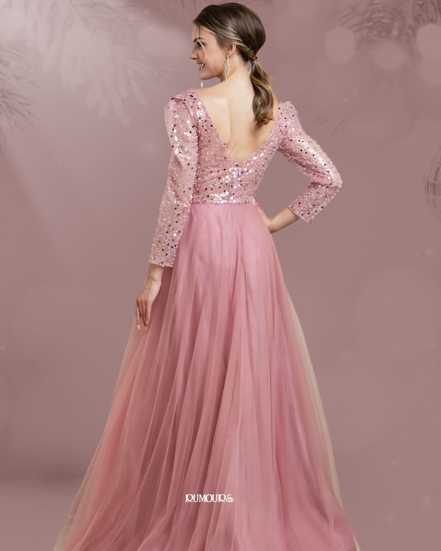 Woman in a pink, sequined gown, facing away, with a tulle skirt, standing against a pink backdrop.
