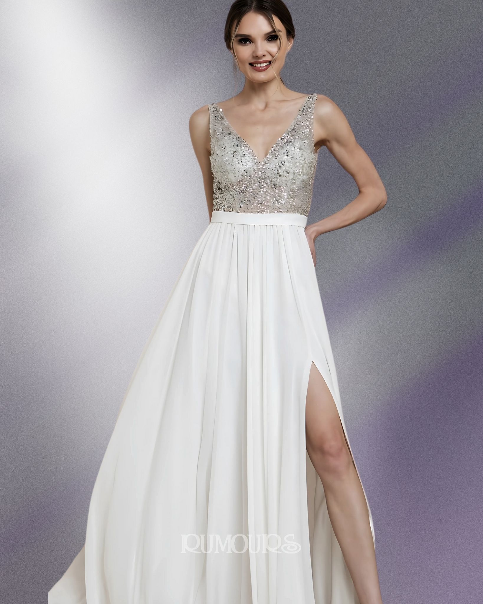 Woman in a white formal dress with a beaded top and a high slit posing in front of a shaded background.