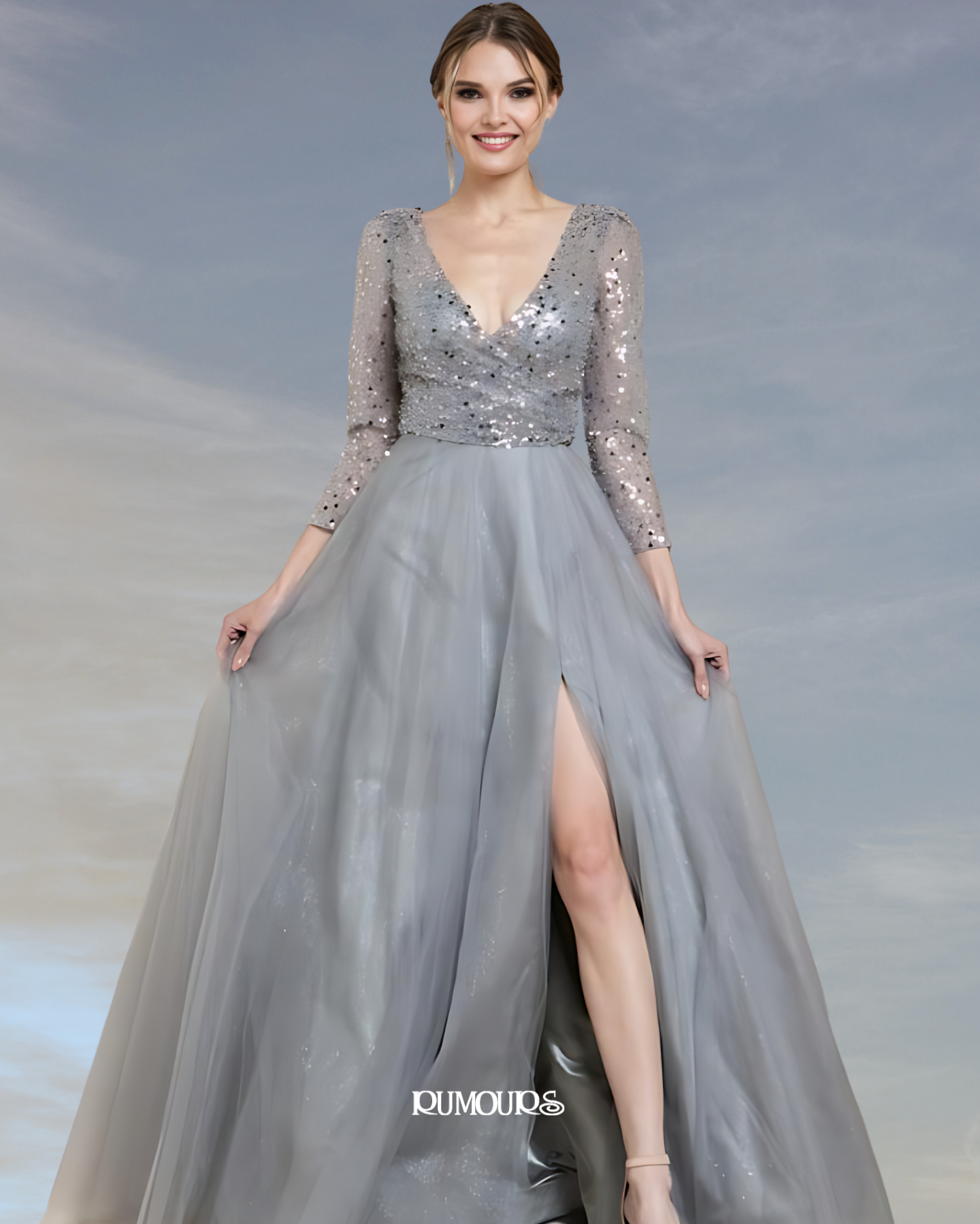 Woman in silver sequined gown with long sleeves and a high slit.