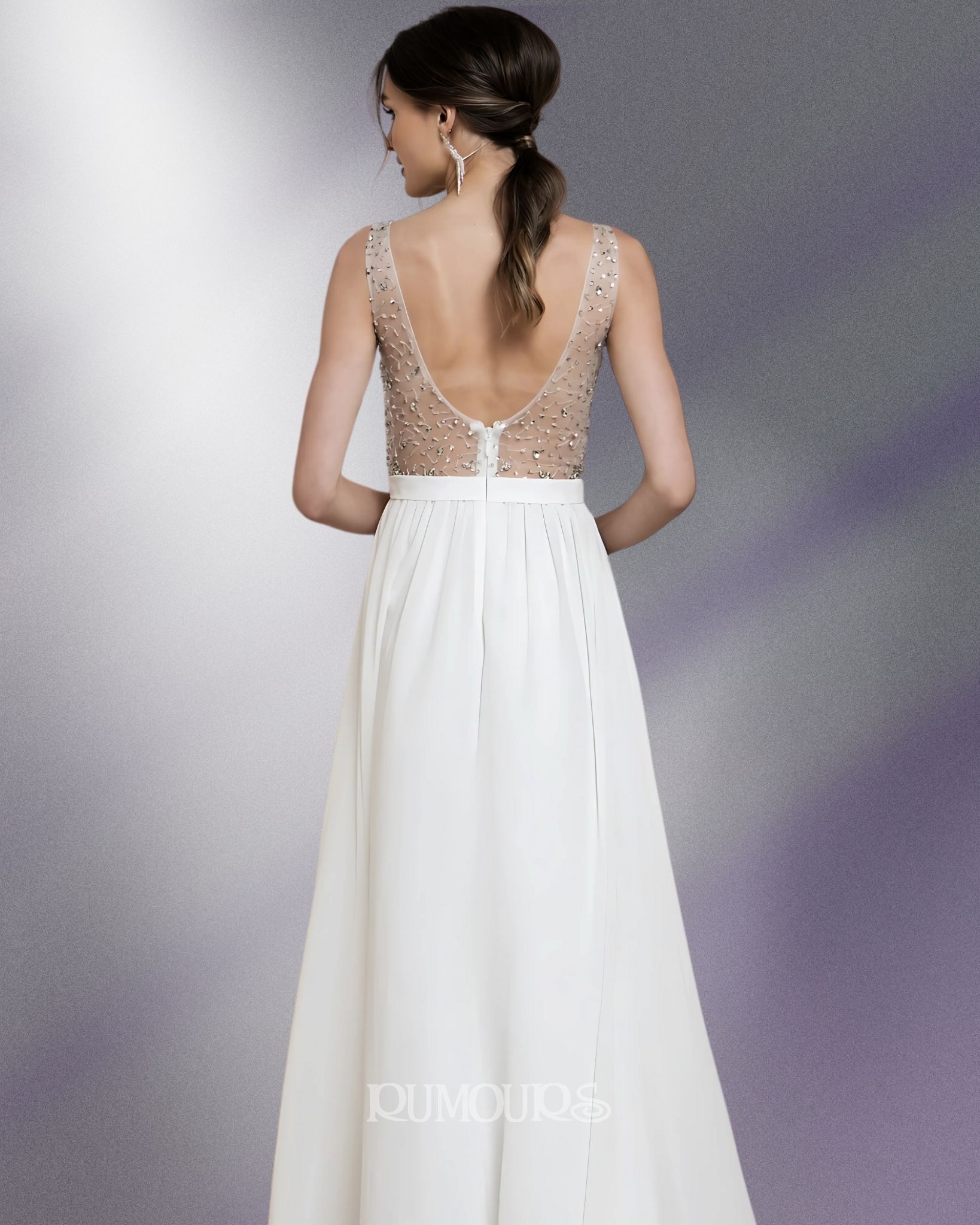 Woman in a white dress, low-back, jeweled bodice, standing against a blurred background.