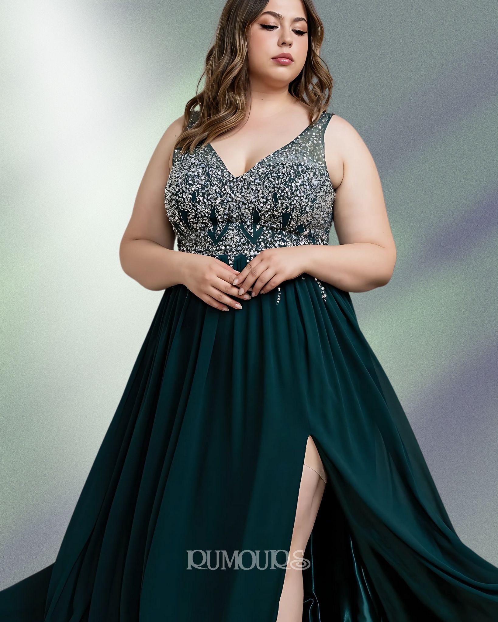 Woman in a dark green formal gown with beaded bodice and a thigh-high slit, posing against a muted, textured background.