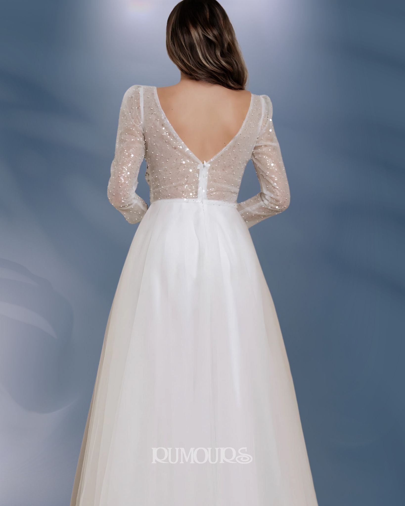 Woman in white wedding dress, back view, sequined bodice, long sleeves, flowing skirt.