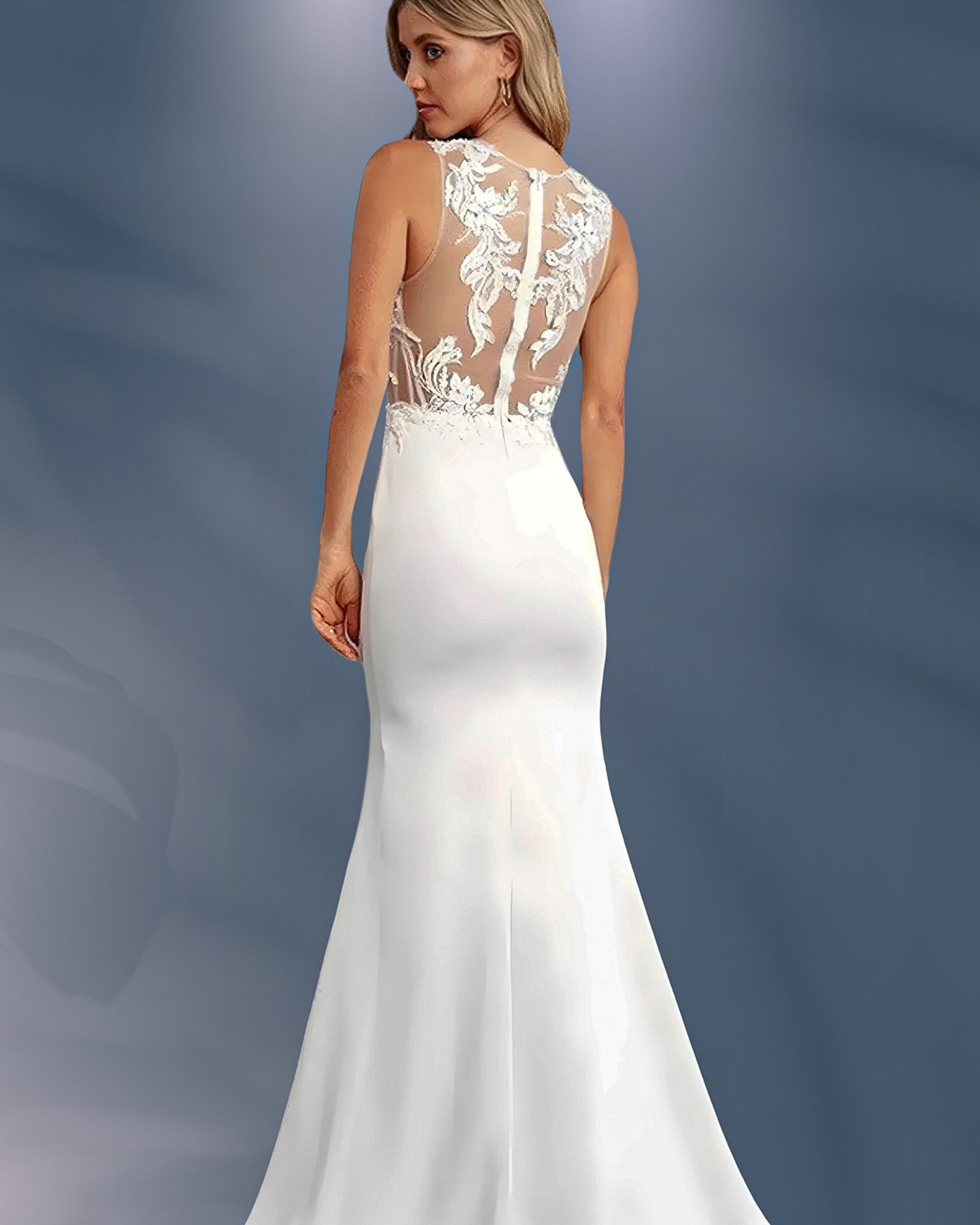 Woman in white wedding dress with lace back, looking over shoulder.