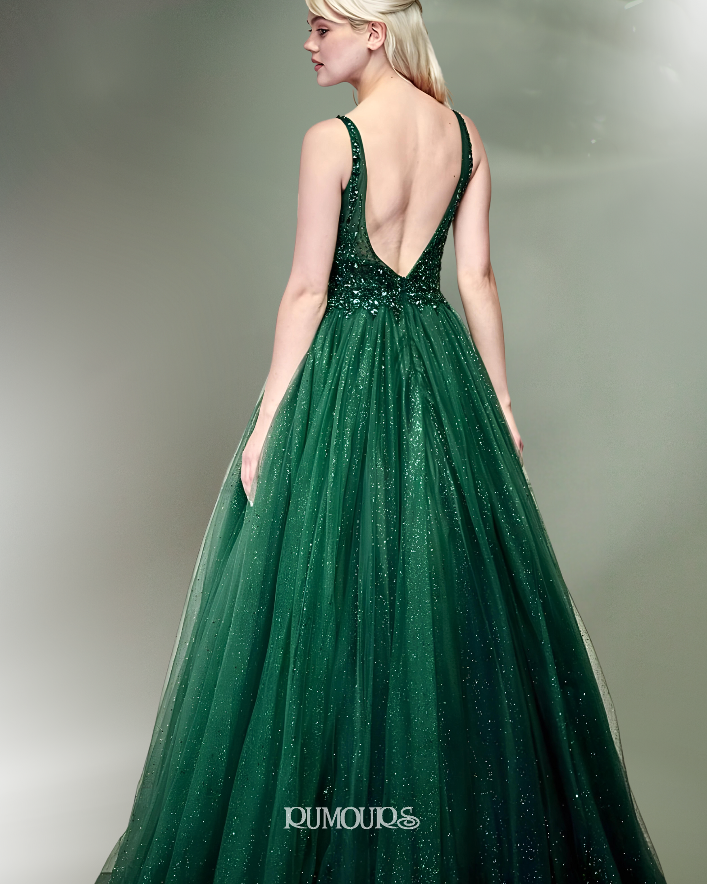 Woman in a green sequin evening gown with a low back, standing.