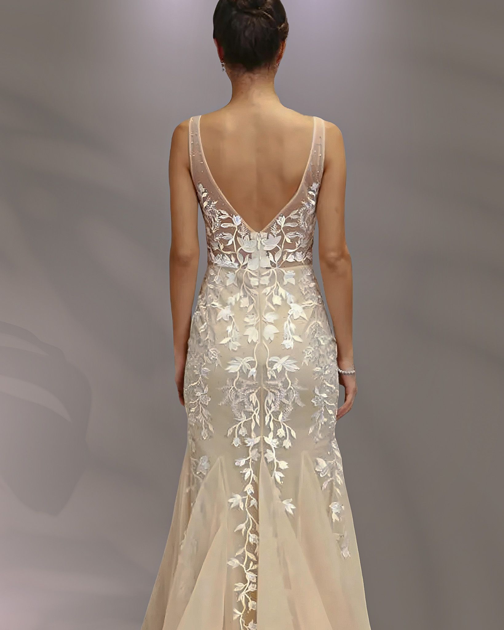Woman in backless, embroidered wedding gown.