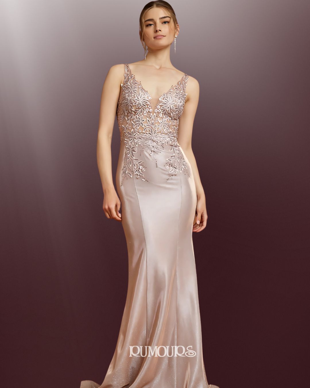 Woman in a formal, light pink gown with embellished bodice, posing against a gradient background.