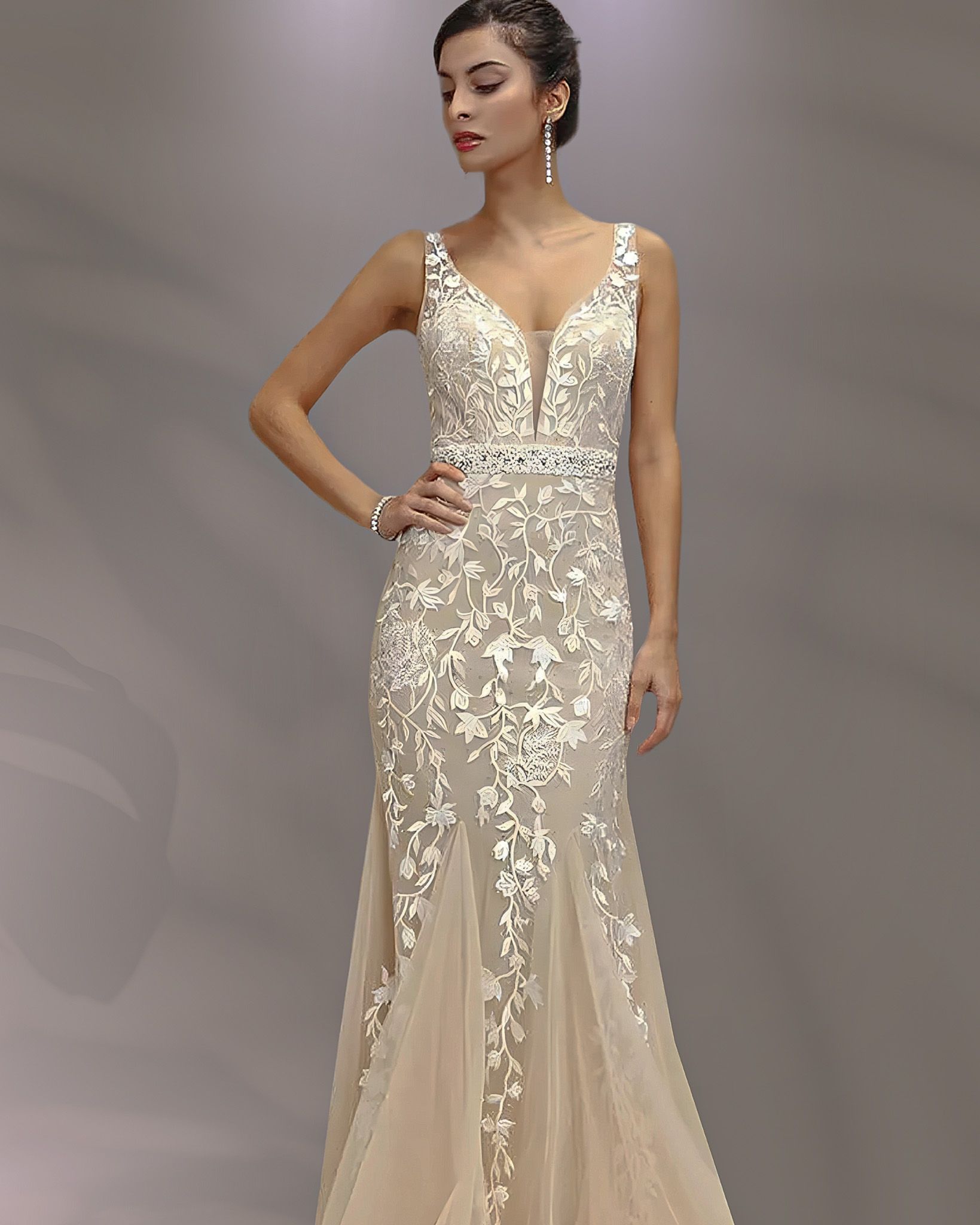 Woman in a white lace wedding dress with a plunging neckline and mermaid skirt, posing indoors.