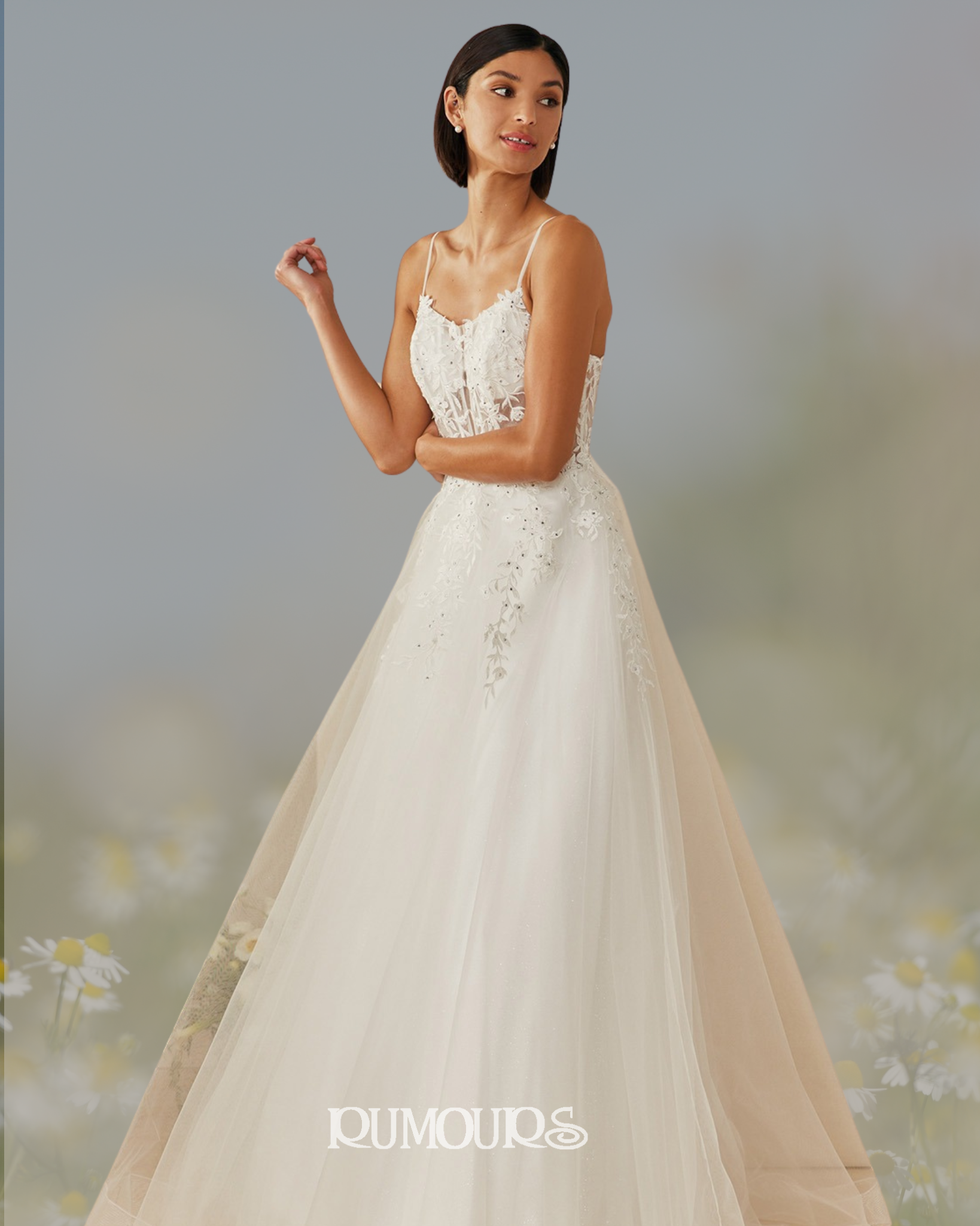 Woman in a white wedding dress with spaghetti straps, a lace bodice, and a full skirt, posing outdoors.