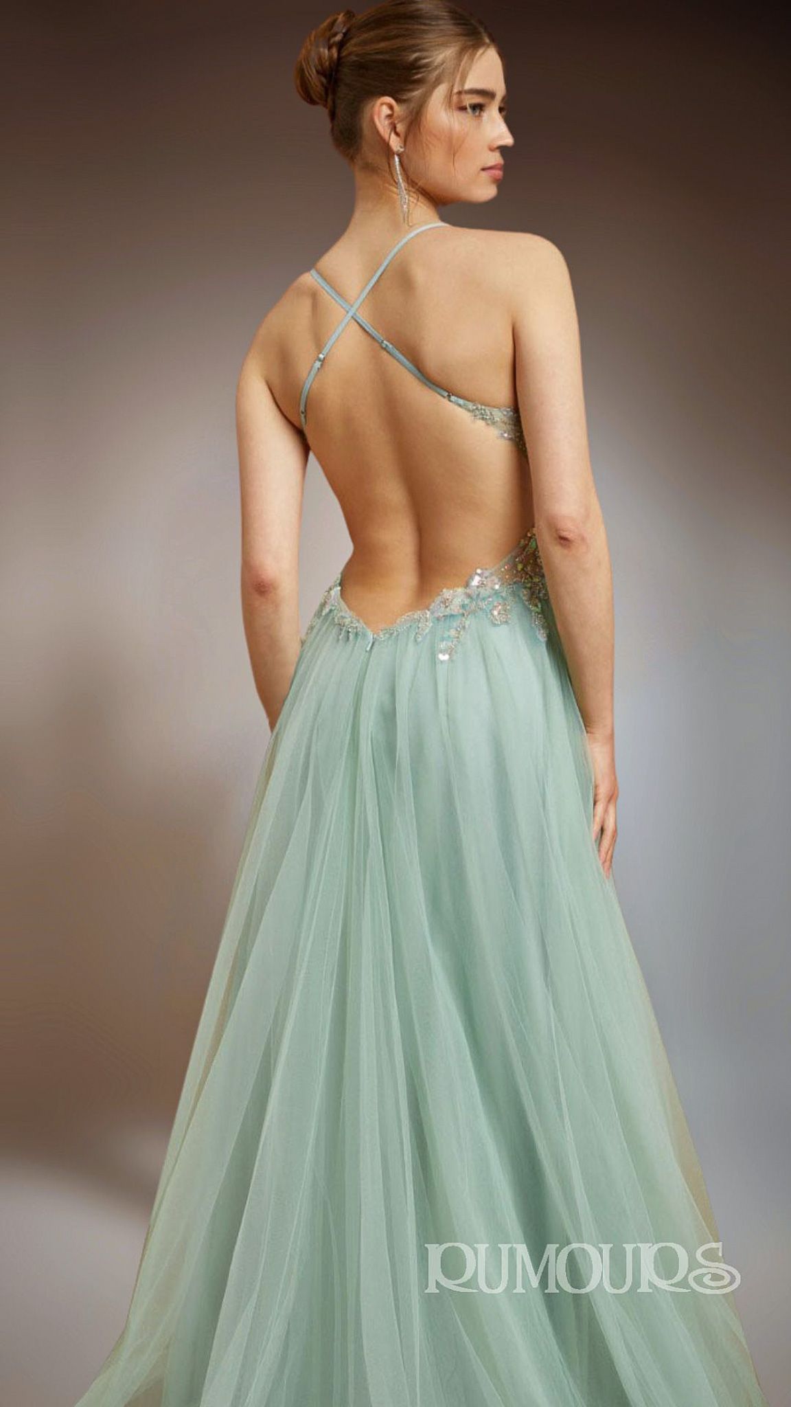Woman in backless, pale green gown, standing and looking right.