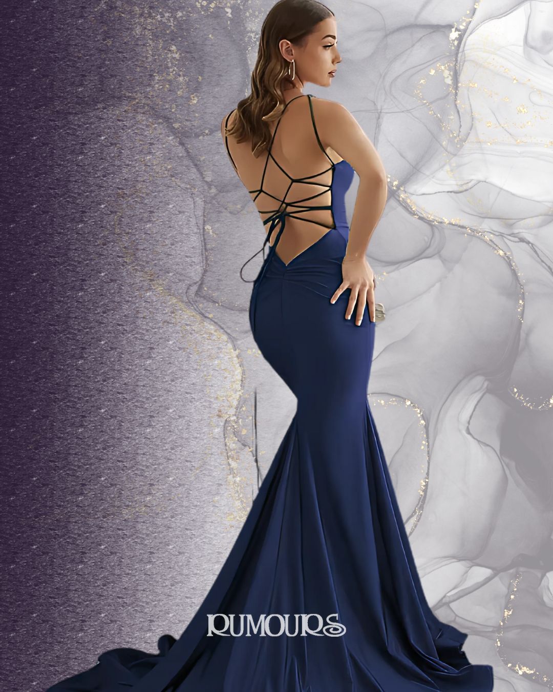 Woman in a navy blue, mermaid-style evening gown with a laced-up back, posing.
