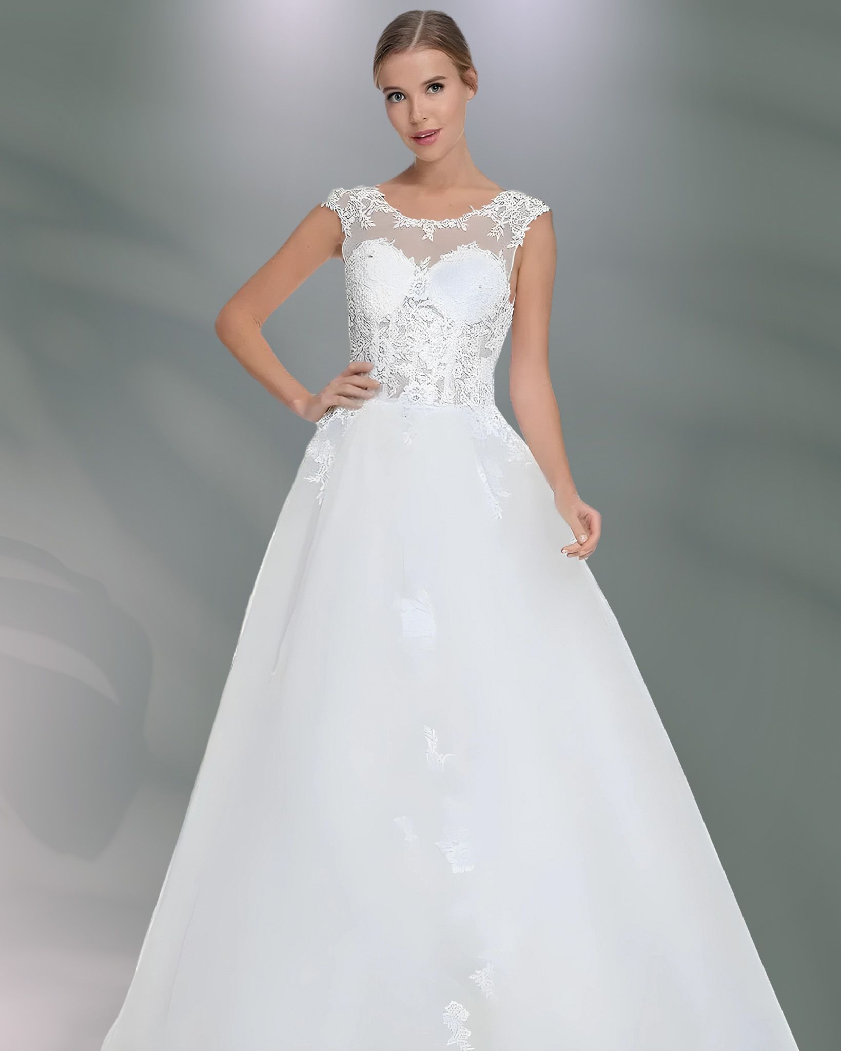Woman in a white wedding dress, posing. Dress features floral lace, cap sleeves, and a full skirt.