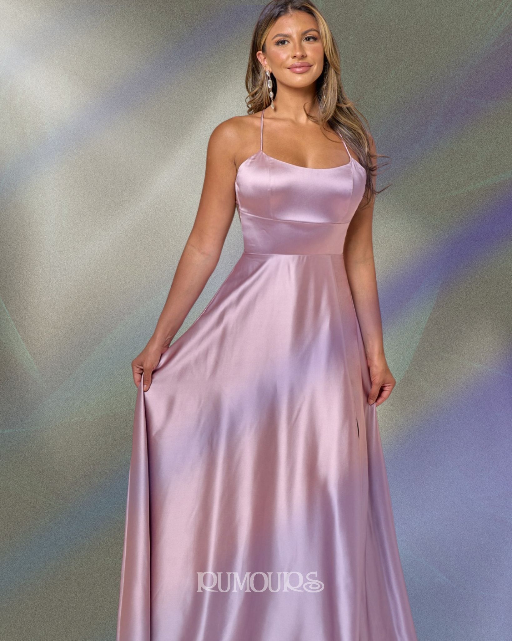 Woman in a pink satin gown, holding the skirt, posing.