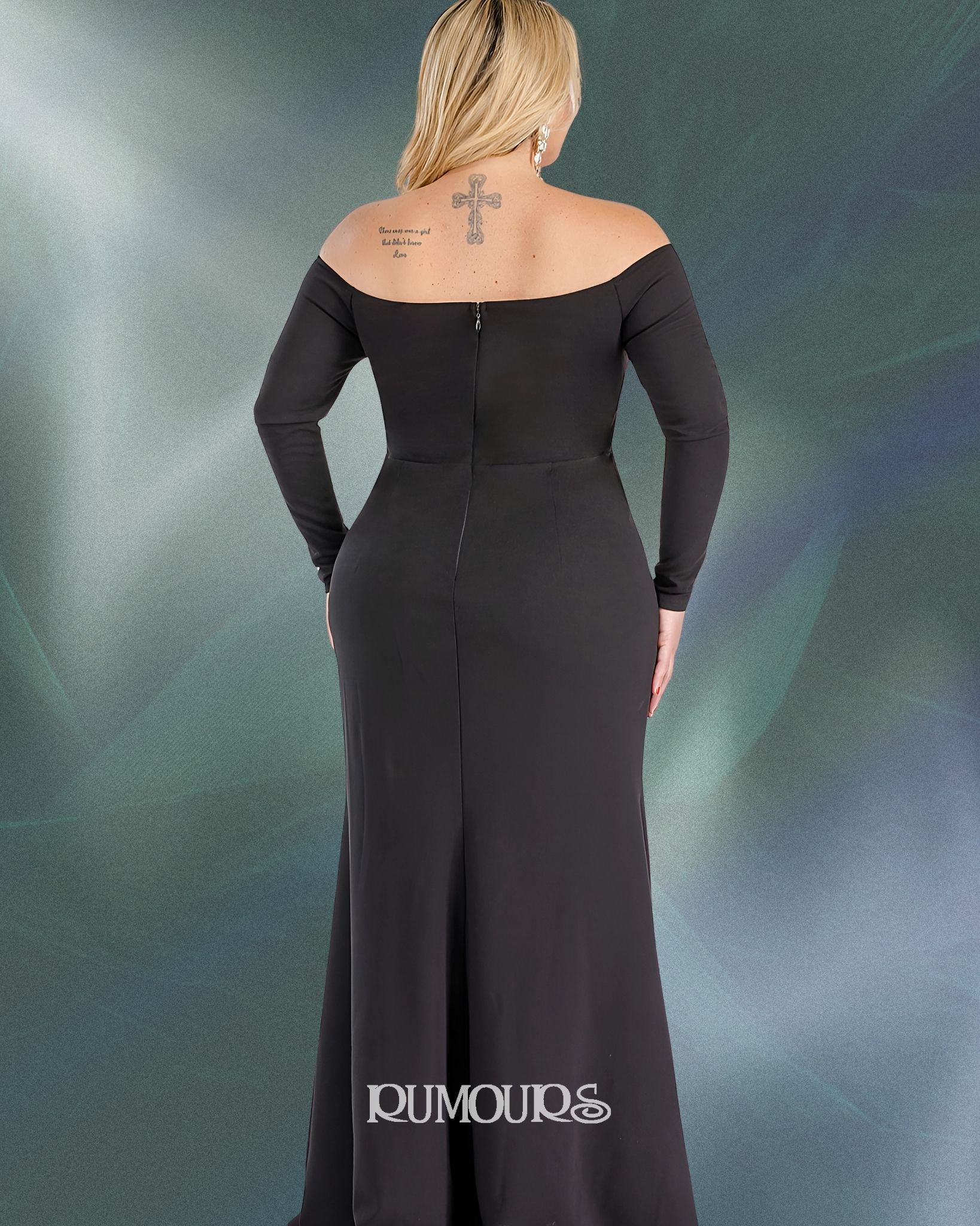 Woman in black off-shoulder gown, standing, back to camera, on a mottled teal background.