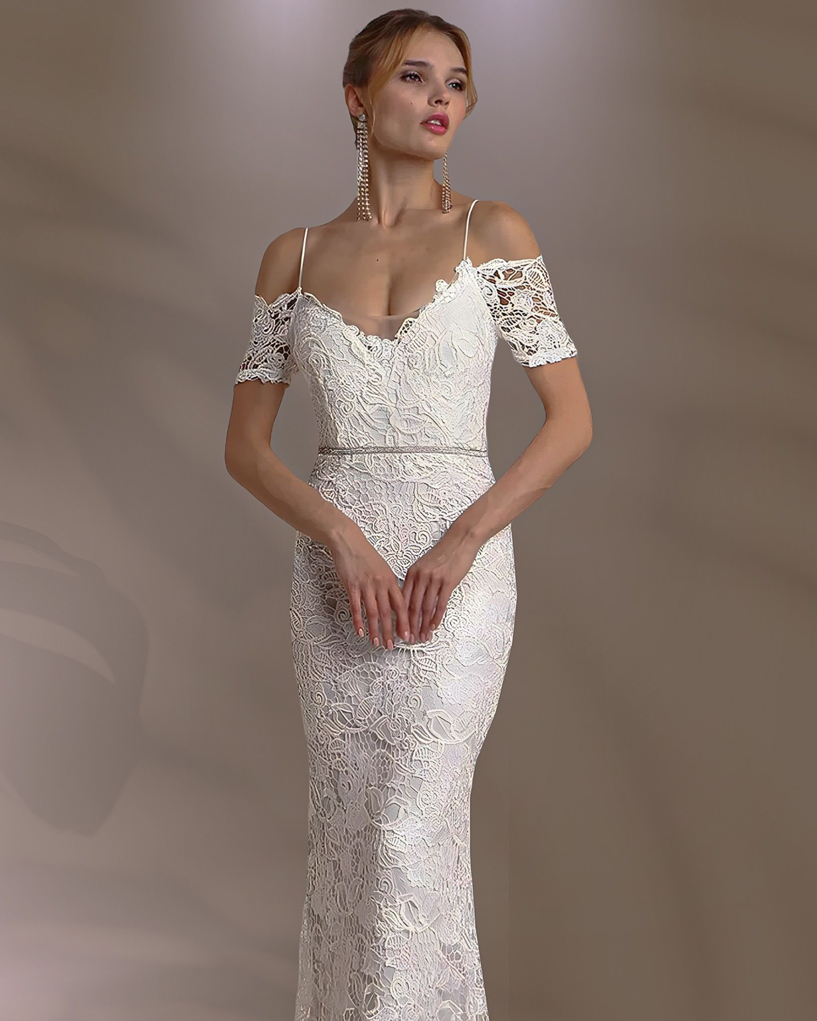 Woman in a white lace off-shoulder dress, small straps, and drop earrings.