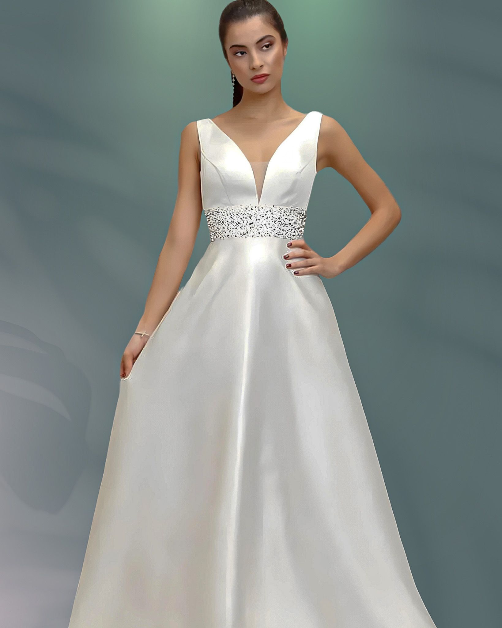 Woman in white wedding dress with V-neckline and embellished waist posing.