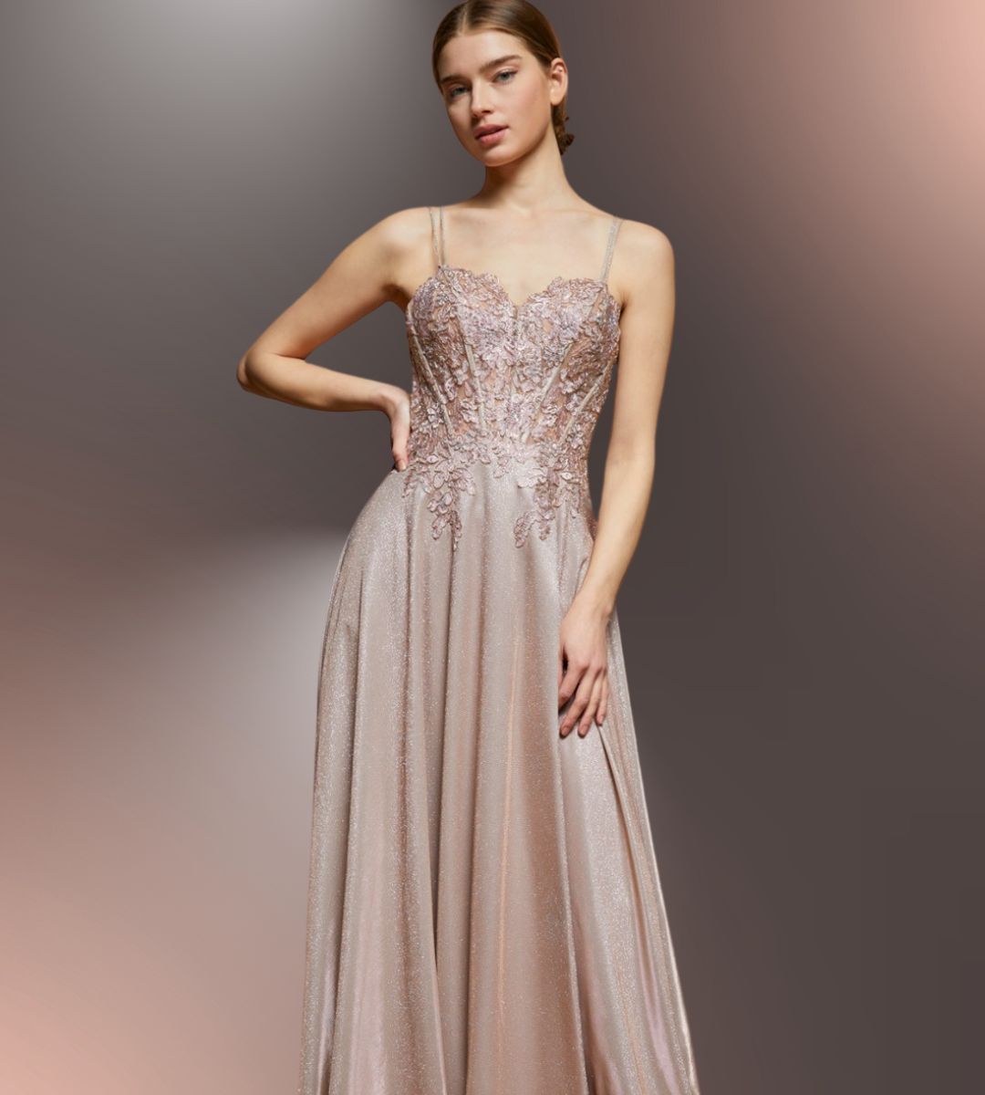 Woman in a formal pink gown with embellished bodice, posing against a gradient background.