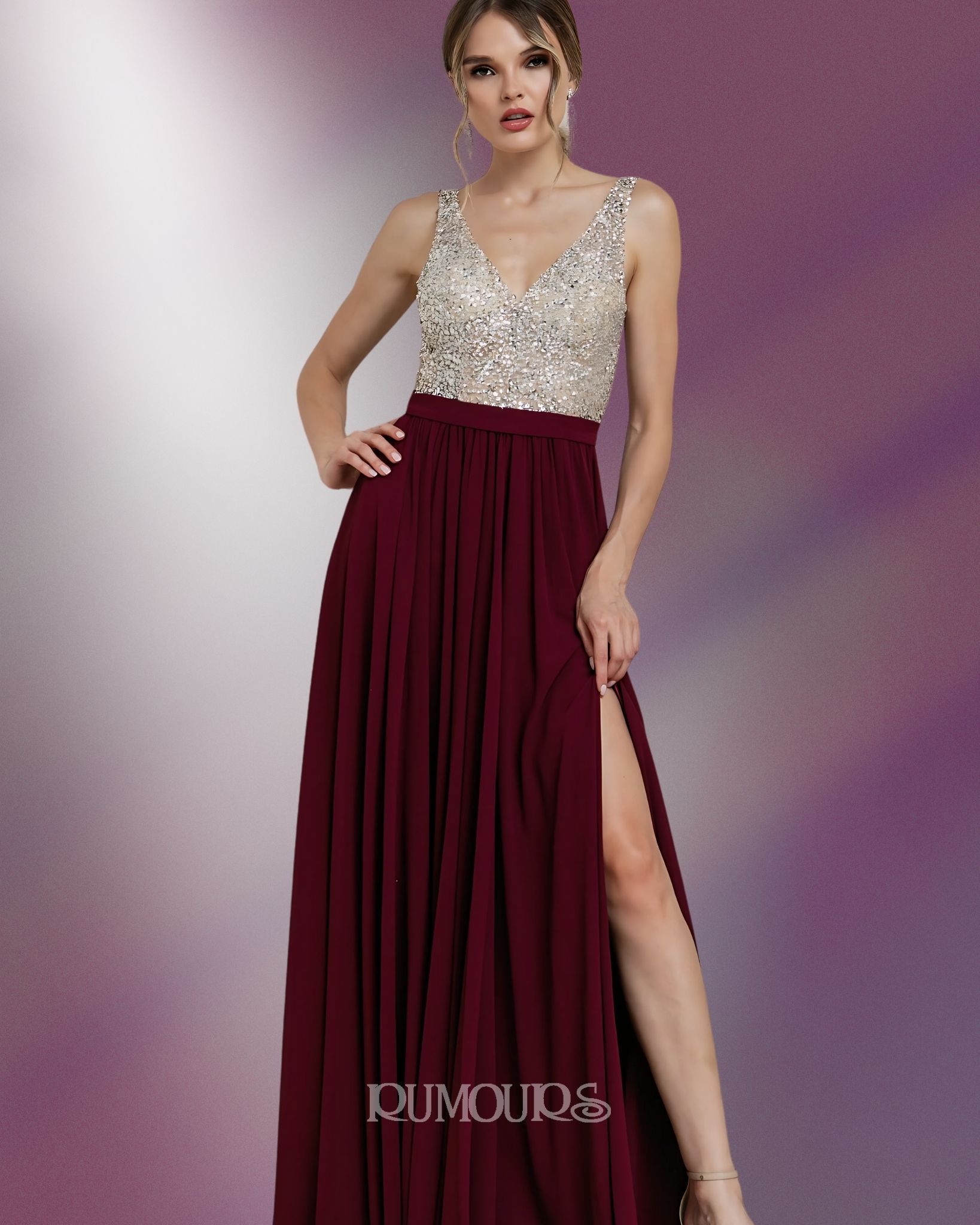 Woman in a burgundy gown with a thigh-high slit and a jeweled bodice, standing with hand on hip.