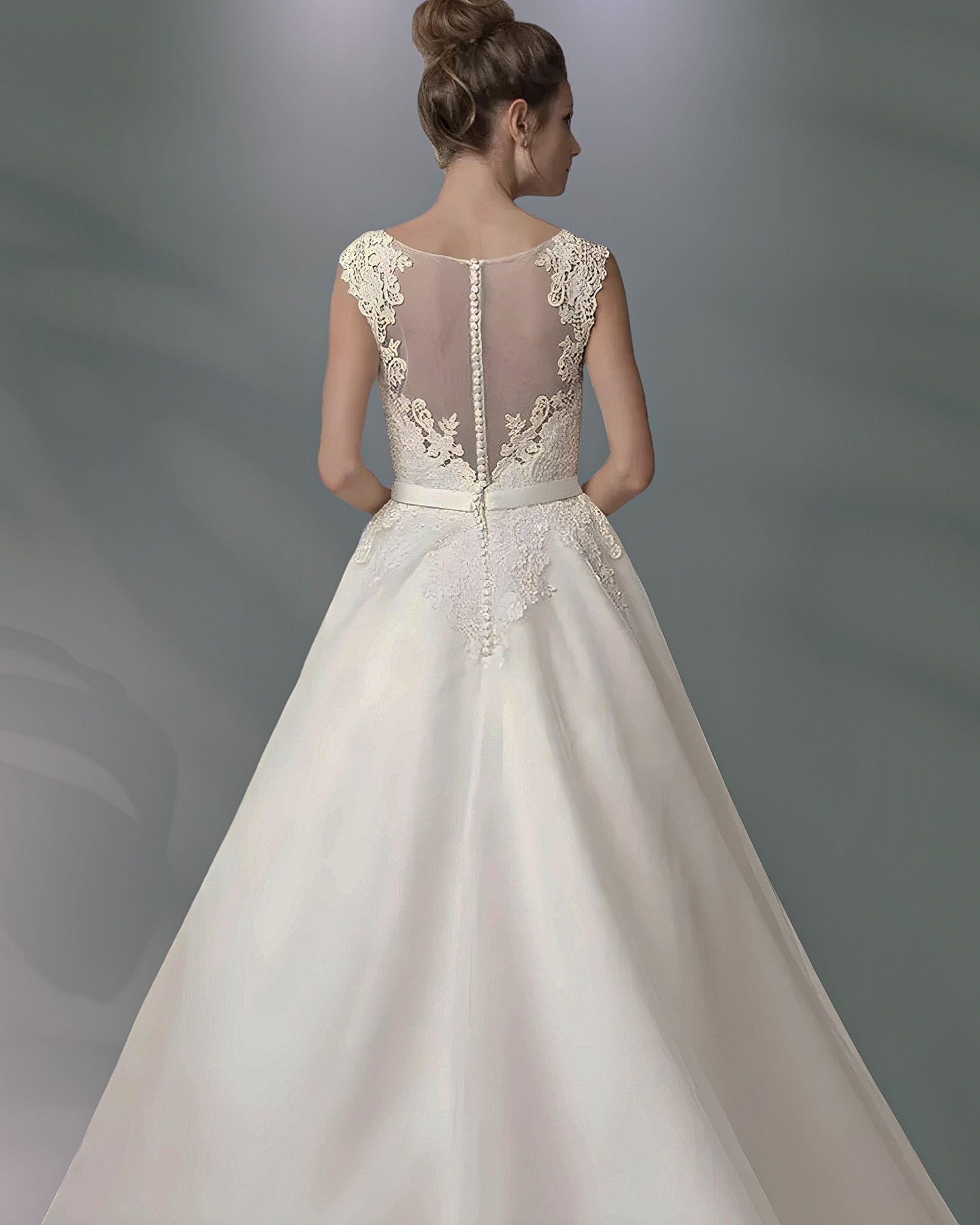 Woman in wedding dress, back view, with sheer lace detail on shoulders and back, and ballgown skirt.