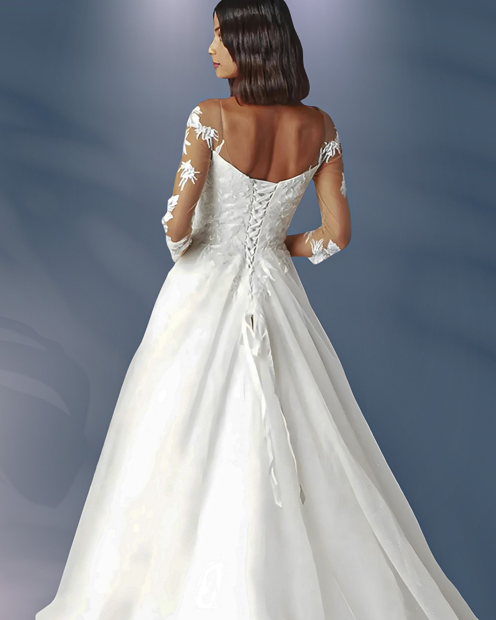 Bride in white wedding dress with lace sleeves and back, posing from behind.