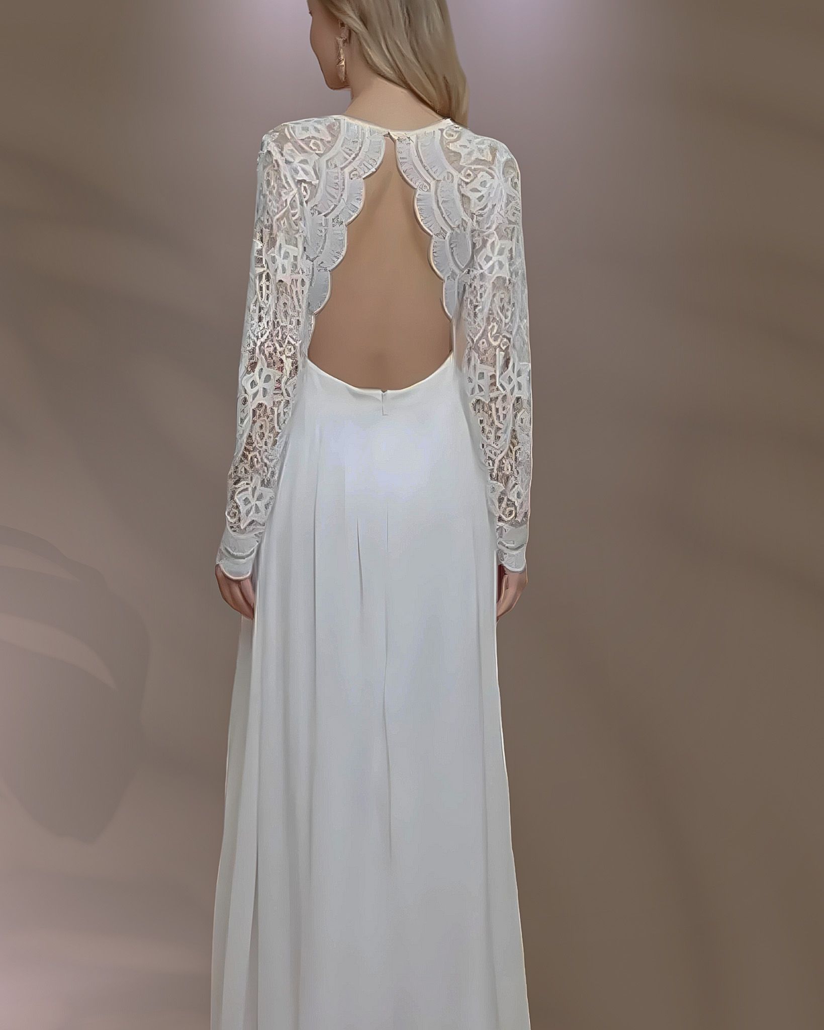 Woman wearing a white wedding dress with open back and lace sleeves.