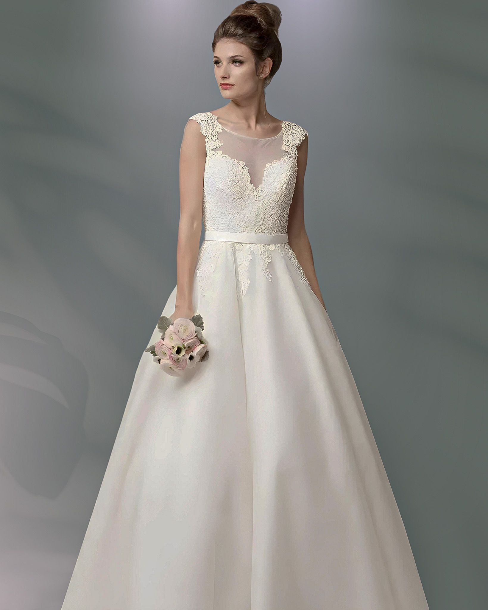 Woman in a white wedding gown holding a bouquet; tulle neckline and full skirt.