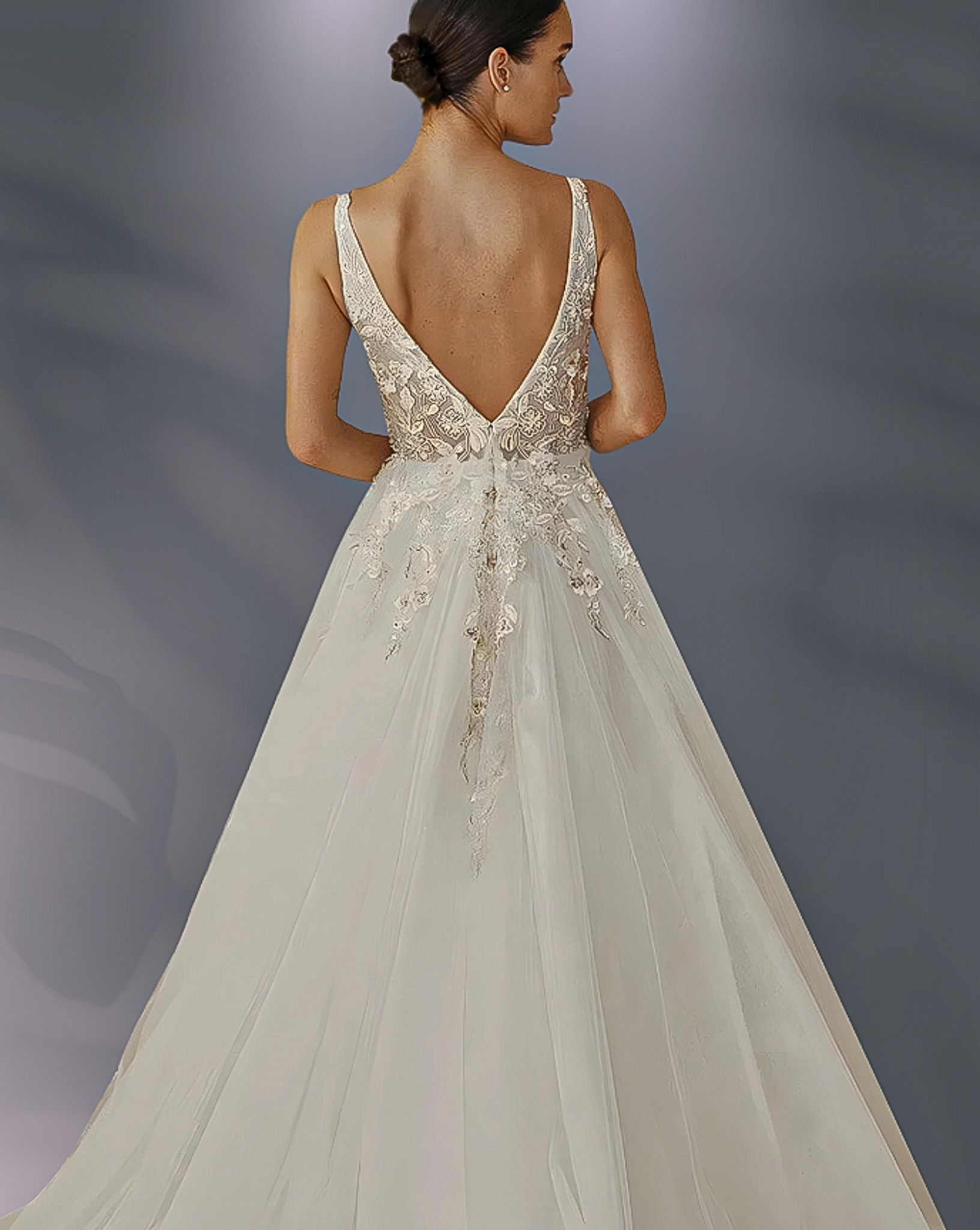 Woman in a wedding dress, back view. Deep V-neck with embellished bodice, tulle skirt.