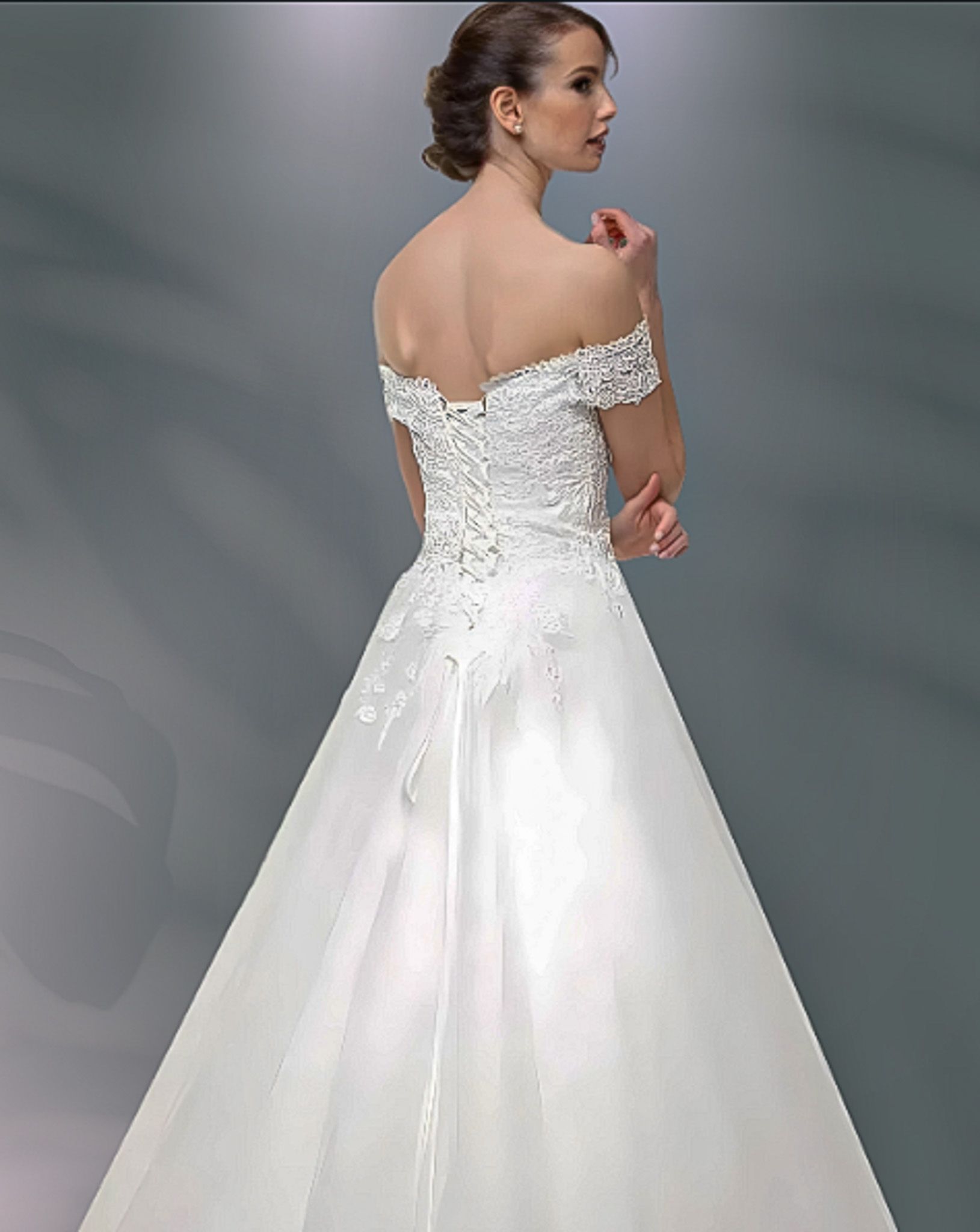 Woman in a white off-the-shoulder wedding dress, back view, with lace bodice and full skirt.