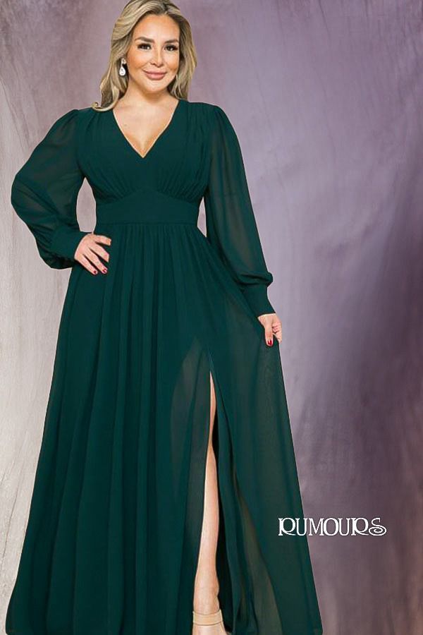 Woman in green formal dress with long sleeves and a high slit.
