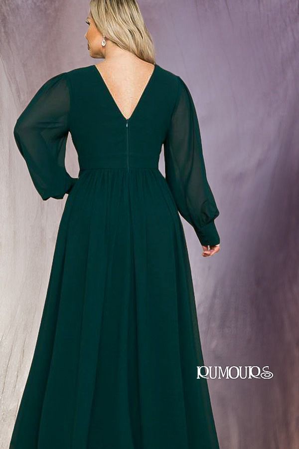 Woman in a dark green dress with long, sheer sleeves. Standing, back view.