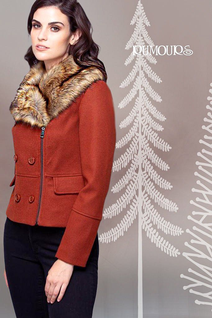 Woman in rust-colored jacket with faux fur collar, standing near Christmas tree graphic.