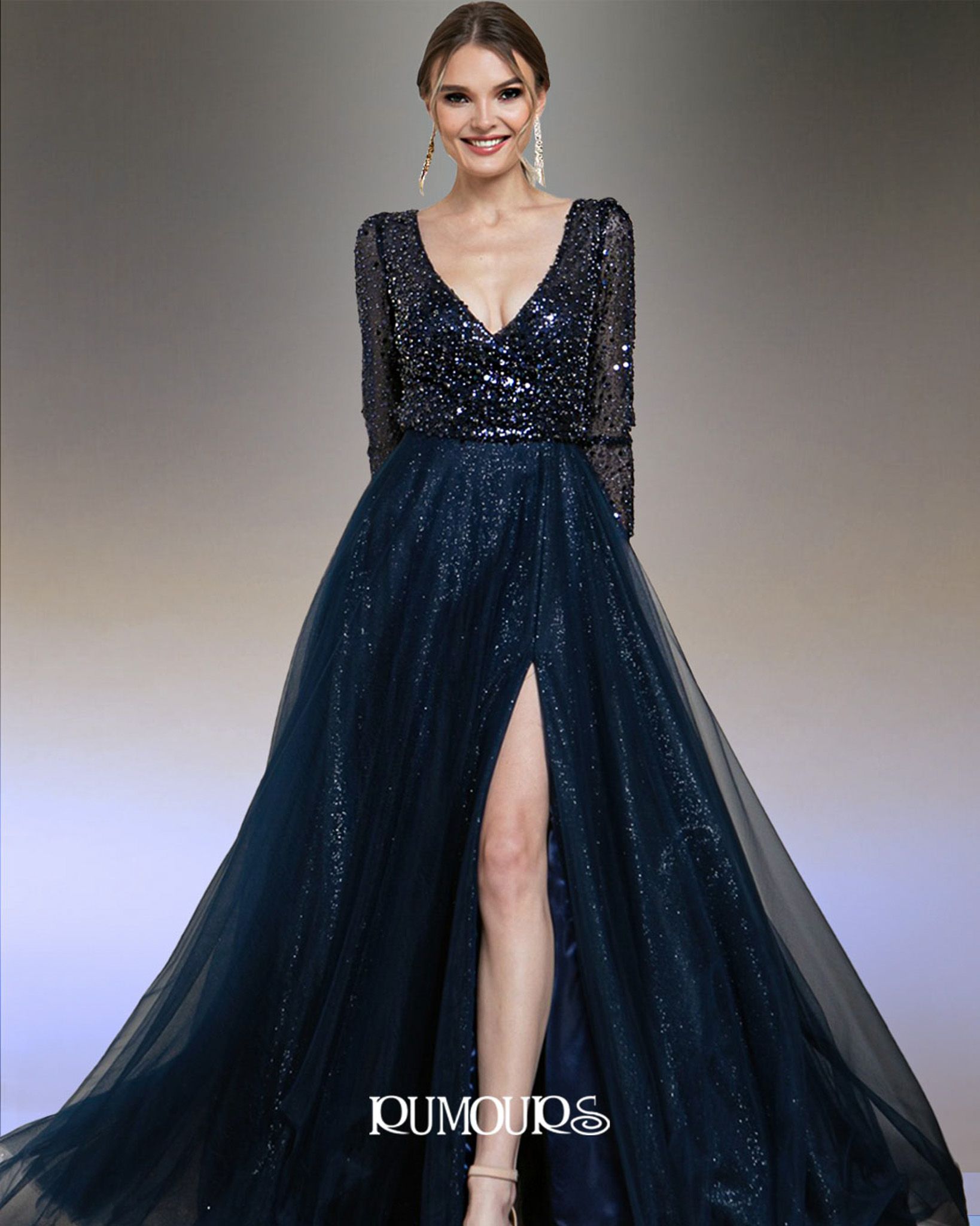 Woman in navy blue sequined gown with long sleeves and high slit, posing indoors.