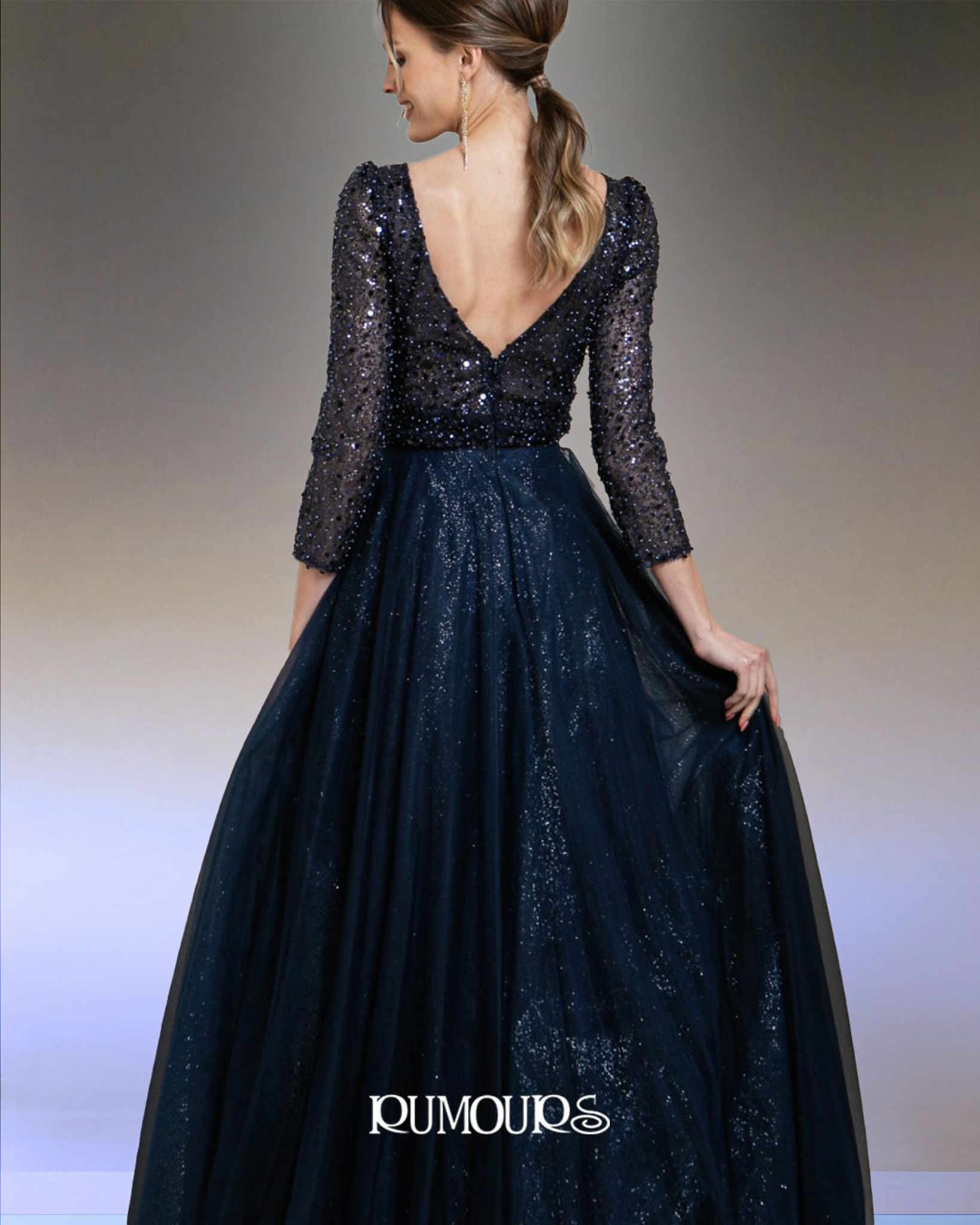 Woman in a dark blue sequined gown with long sleeves and a low back.