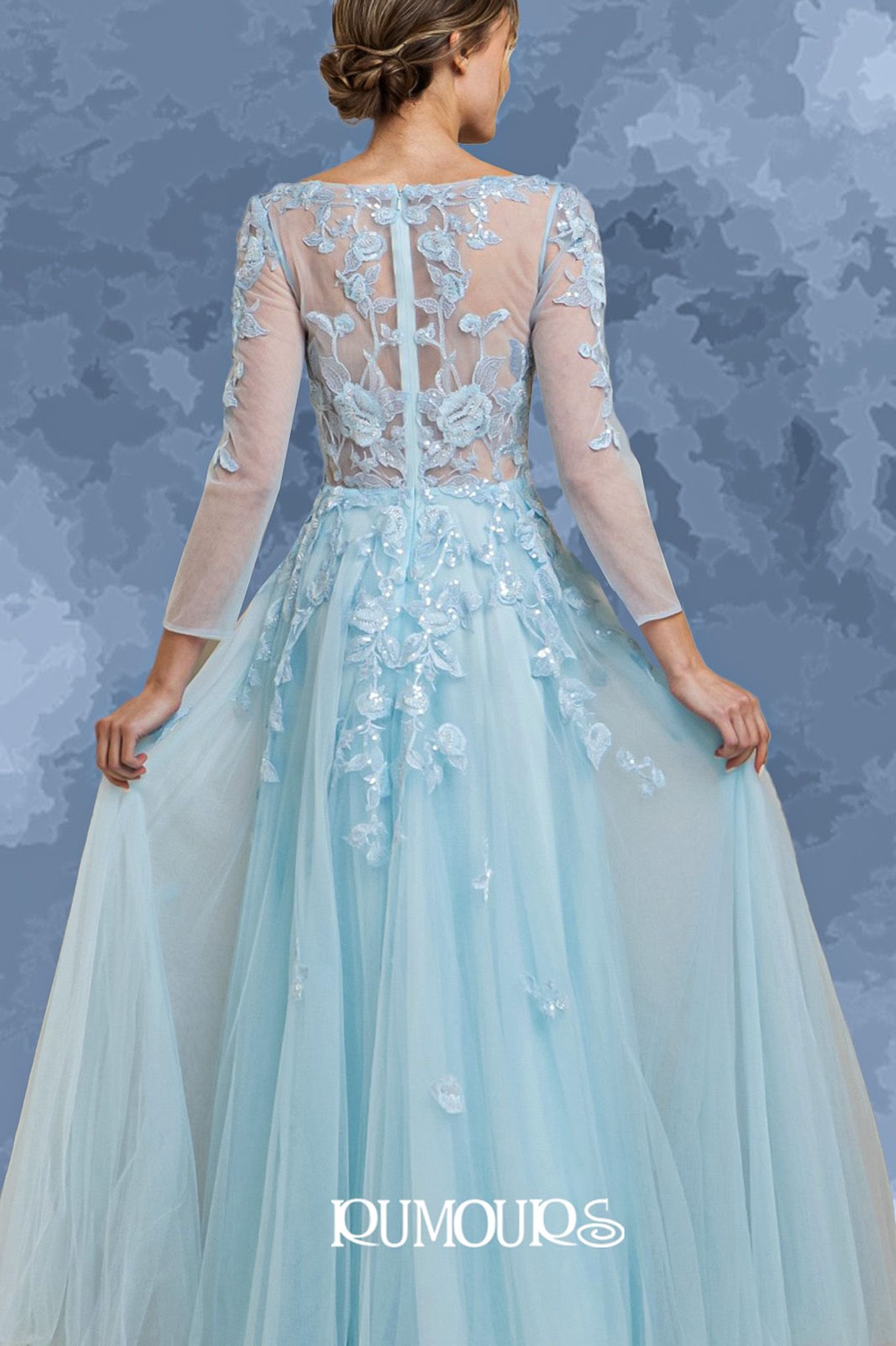 Woman in light blue formal gown with floral detailing, holding out the skirt.