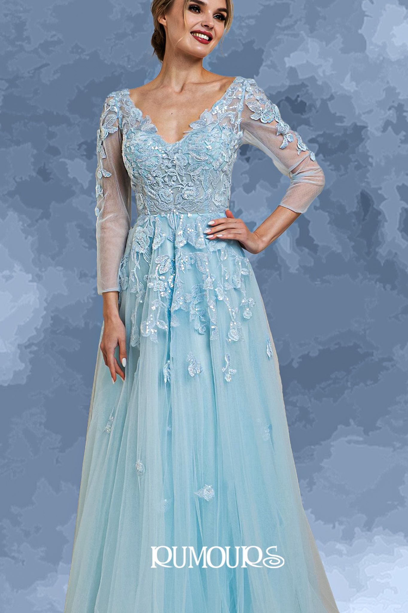 Woman in a light blue formal gown with a V-neck and long sheer sleeves, smiling.