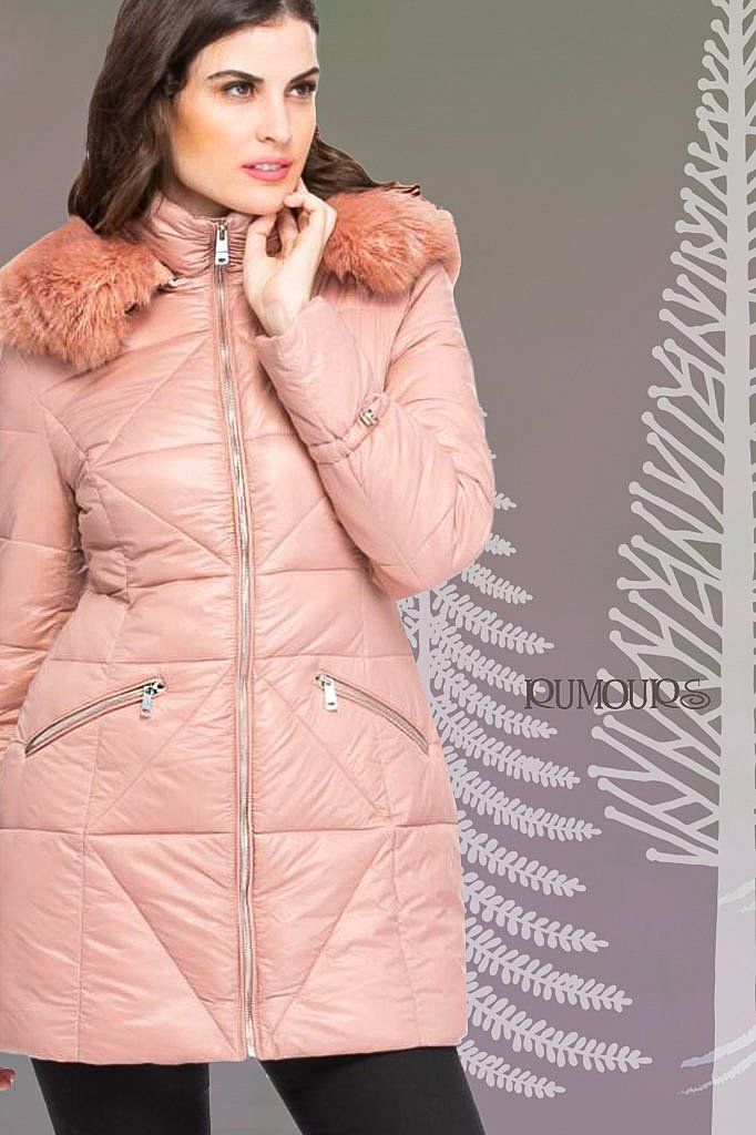 Woman in a pink down coat with fur hood, hand to chin, posing in front of a gray background.