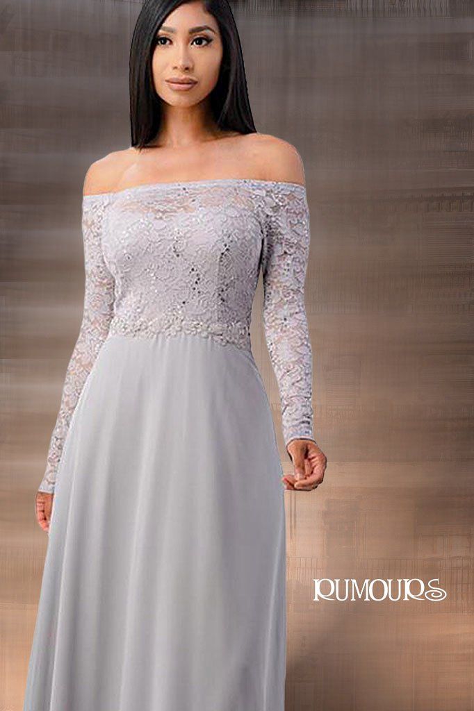 Woman in a gray off-the-shoulder lace dress with long sleeves, standing in front of a blurred background.