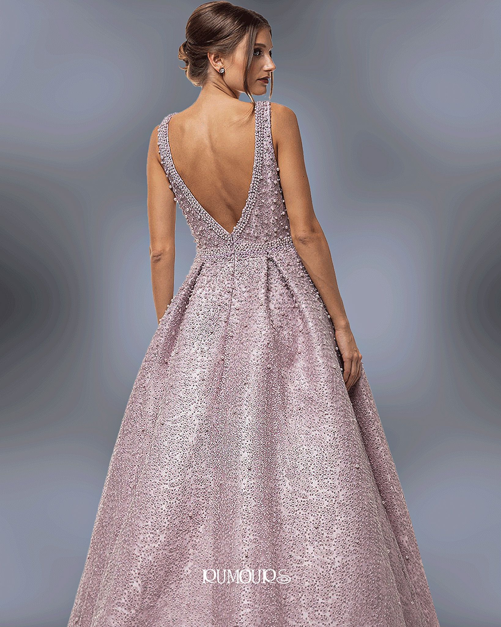 Woman in a sparkling pink gown with a low back, standing indoors.