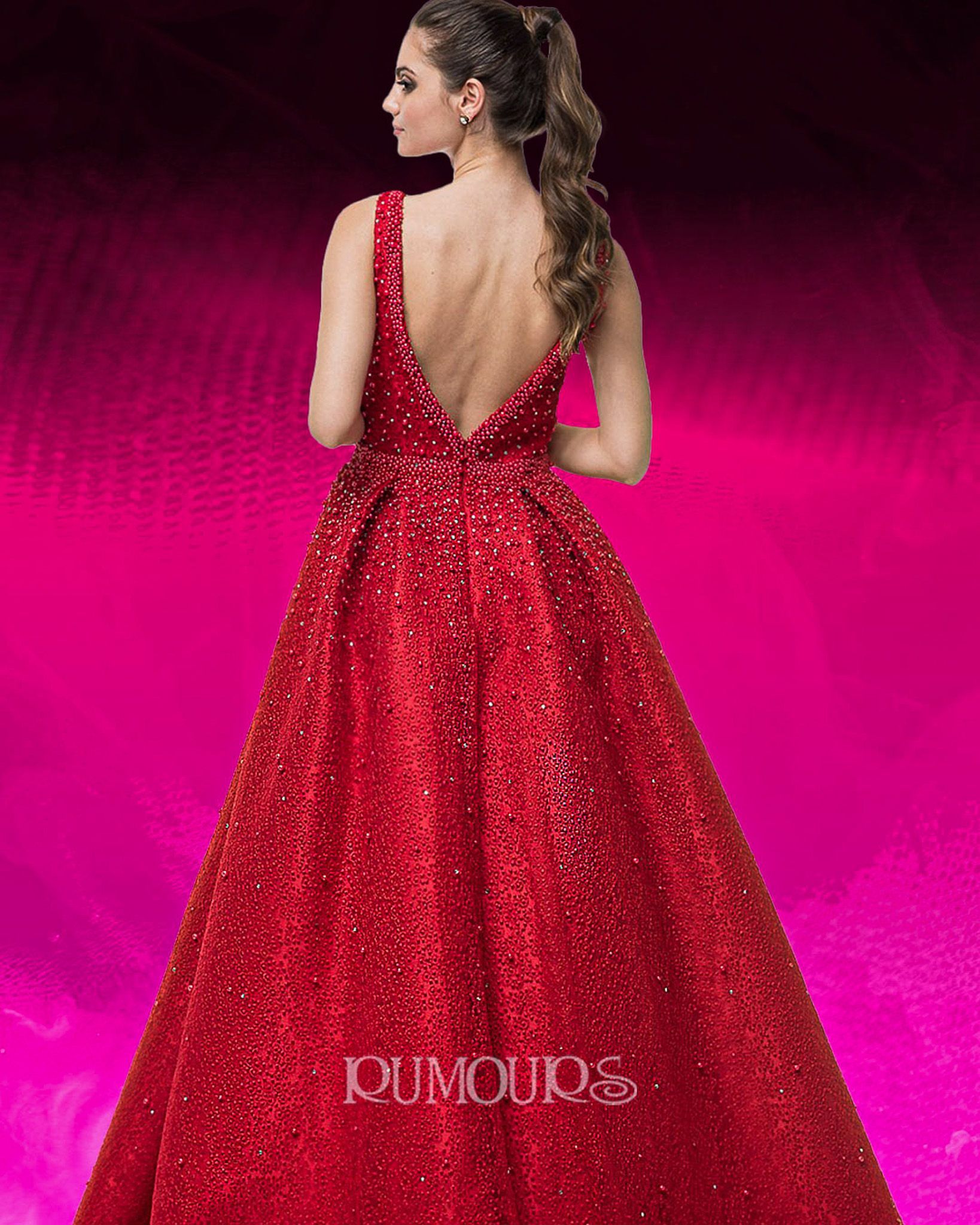 Woman in a red sequined gown with a low back, standing in front of a pink background.