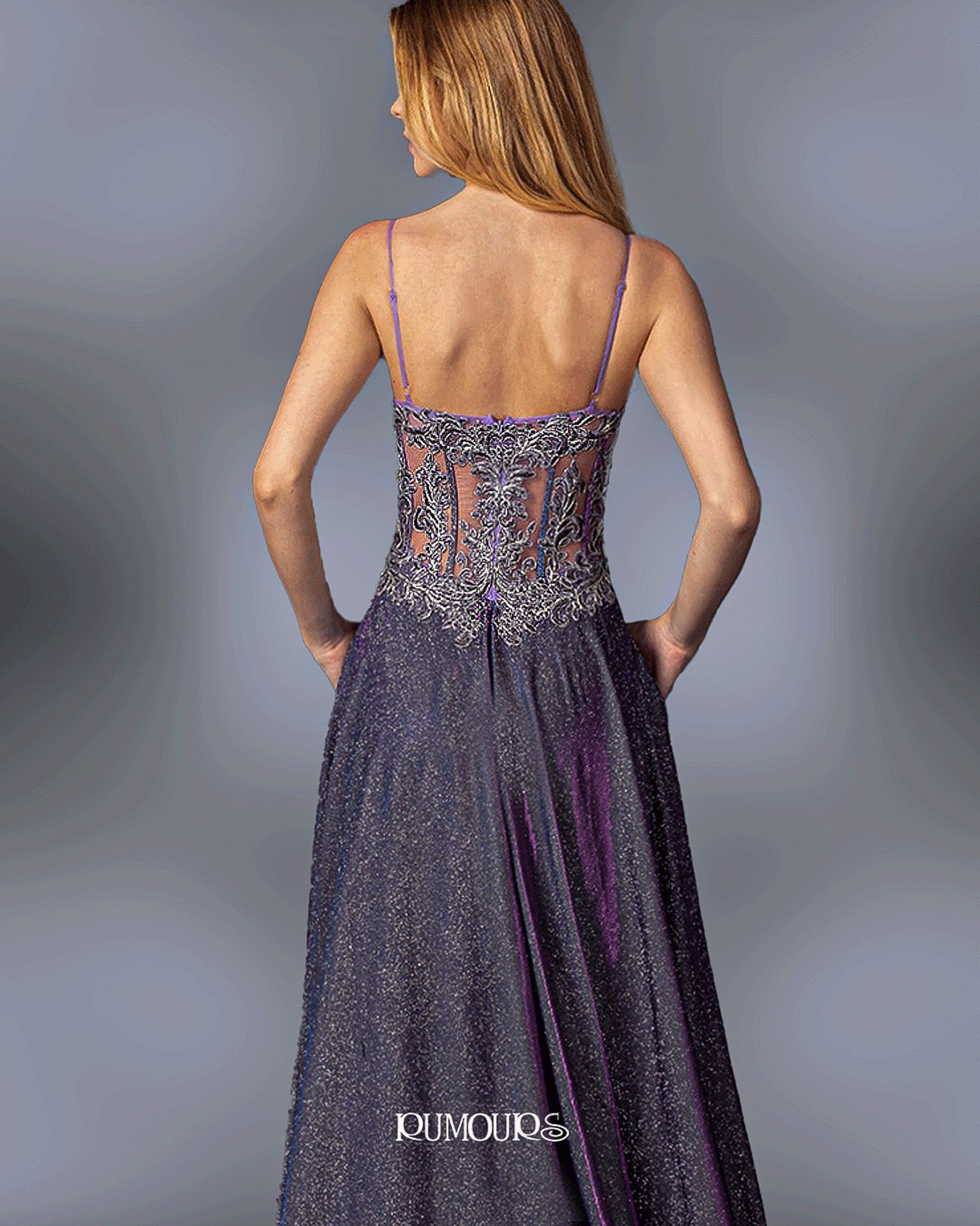Woman in a sparkly purple formal gown, with thin straps and a detailed bodice, standing in a studio.
