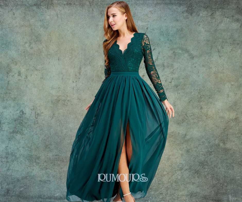 Woman wearing a long, dark green dress with a lace bodice and long sleeves, with a high slit in the skirt.