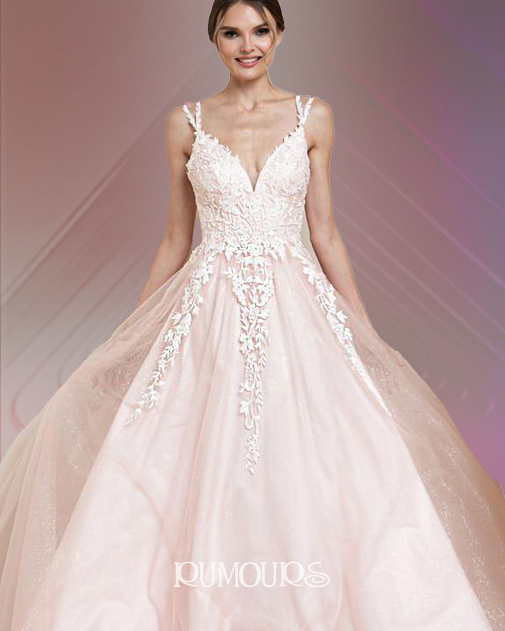 Woman in a blush-colored wedding gown with lace bodice and spaghetti straps, smiling.
