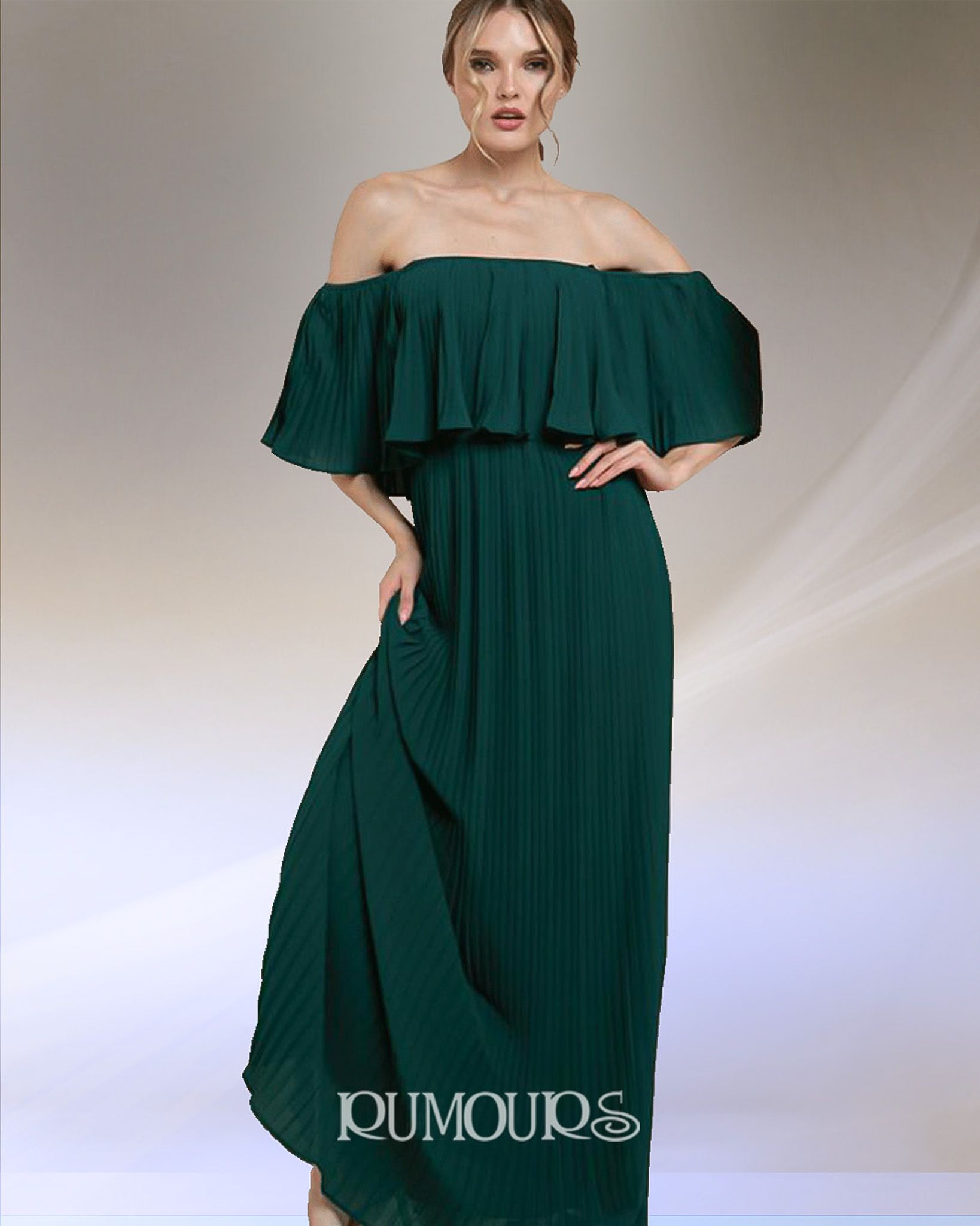 Woman in a dark green off-the-shoulder pleated maxi dress. She has her hand on her hip and a neutral expression.