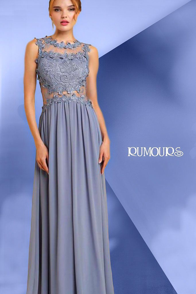Woman in a formal blue dress with lace bodice, posing in a studio with a blue background.