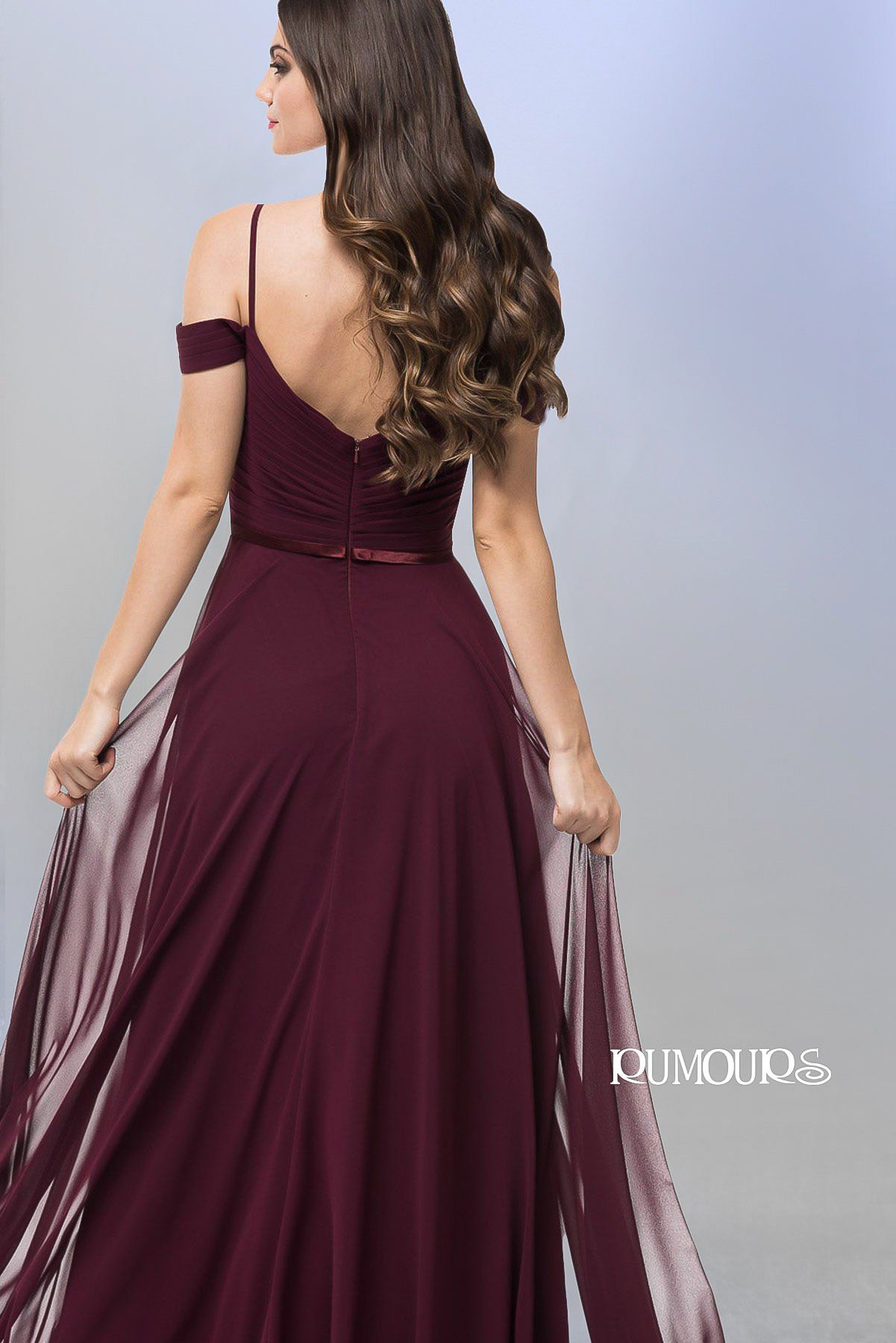 Woman in a dark red evening gown, back view, with flowing skirt and off-the-shoulder detail.