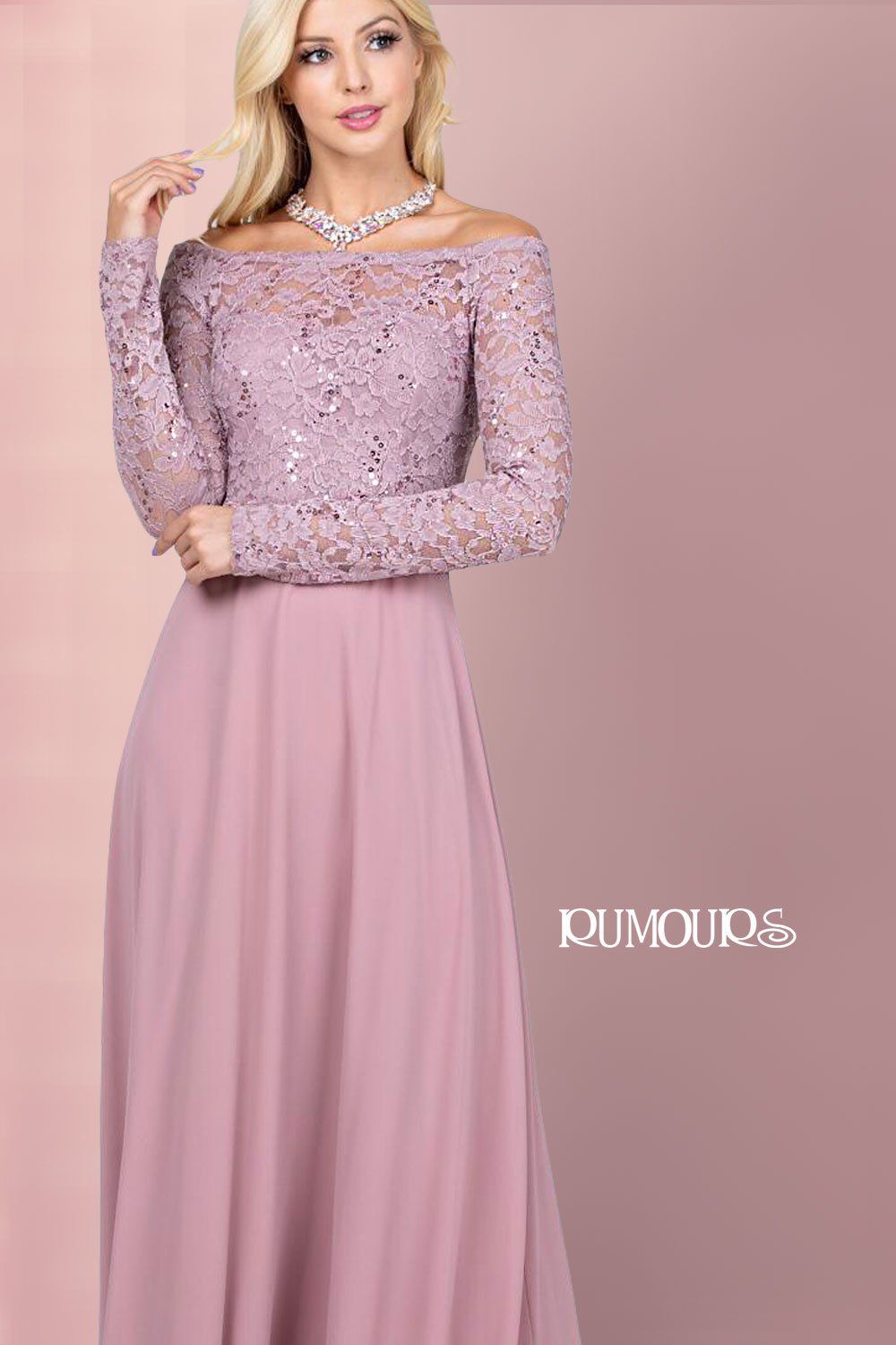 Woman wearing a mauve off-the-shoulder lace top and a flowing skirt, standing in front of a pink background.